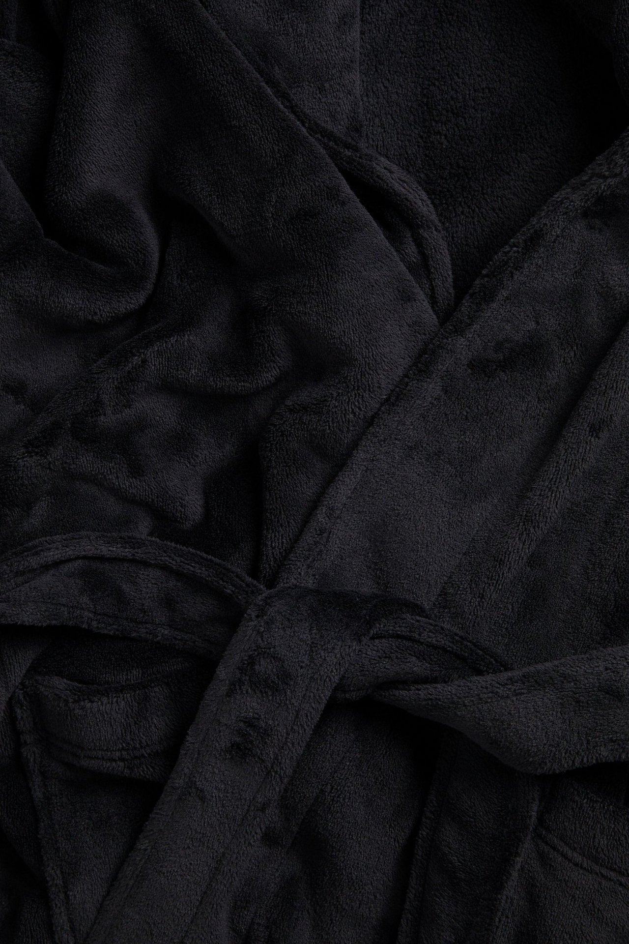 Zbliżenie czarnego szlafroka polarowego z zawiązanym paskiem i przednią kieszenią.