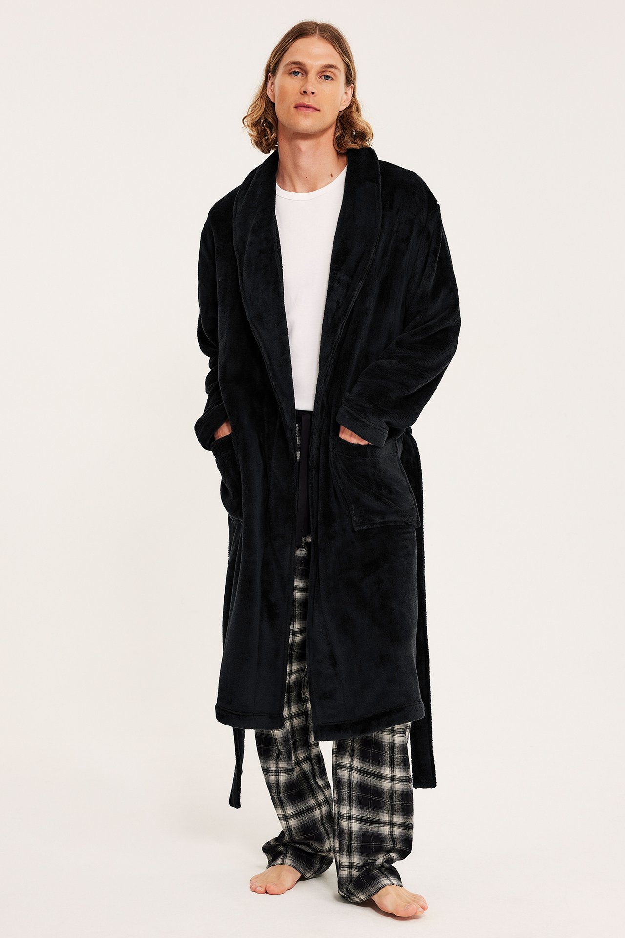 Front view: Mann har på seg svart fleece morgenkåpe med belte, over hvit t-skjorte og rutete pysjamas.