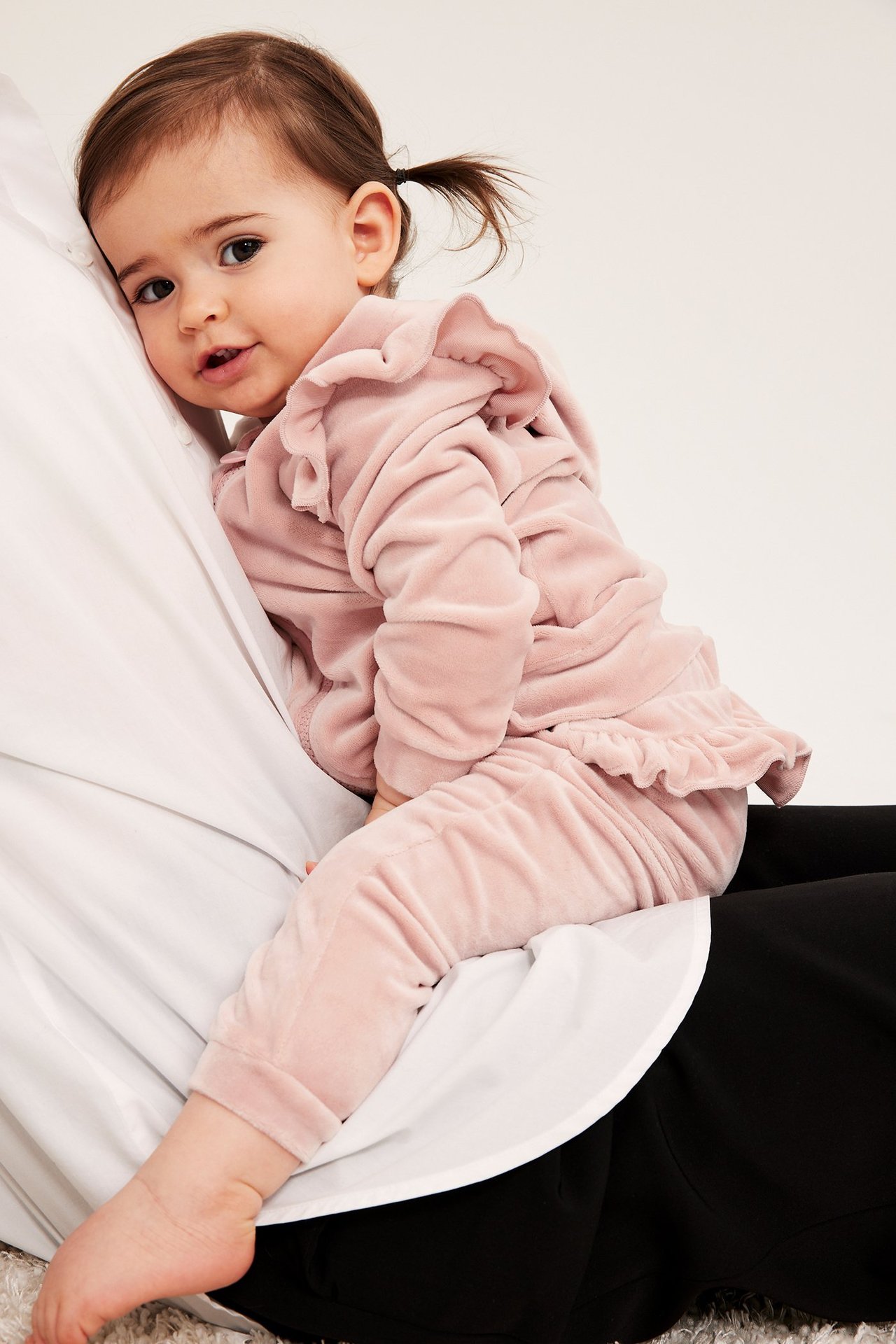 Sidebilde av en baby i rosa velour-joggebukse med elastiske mansjetter og en volangtopp.