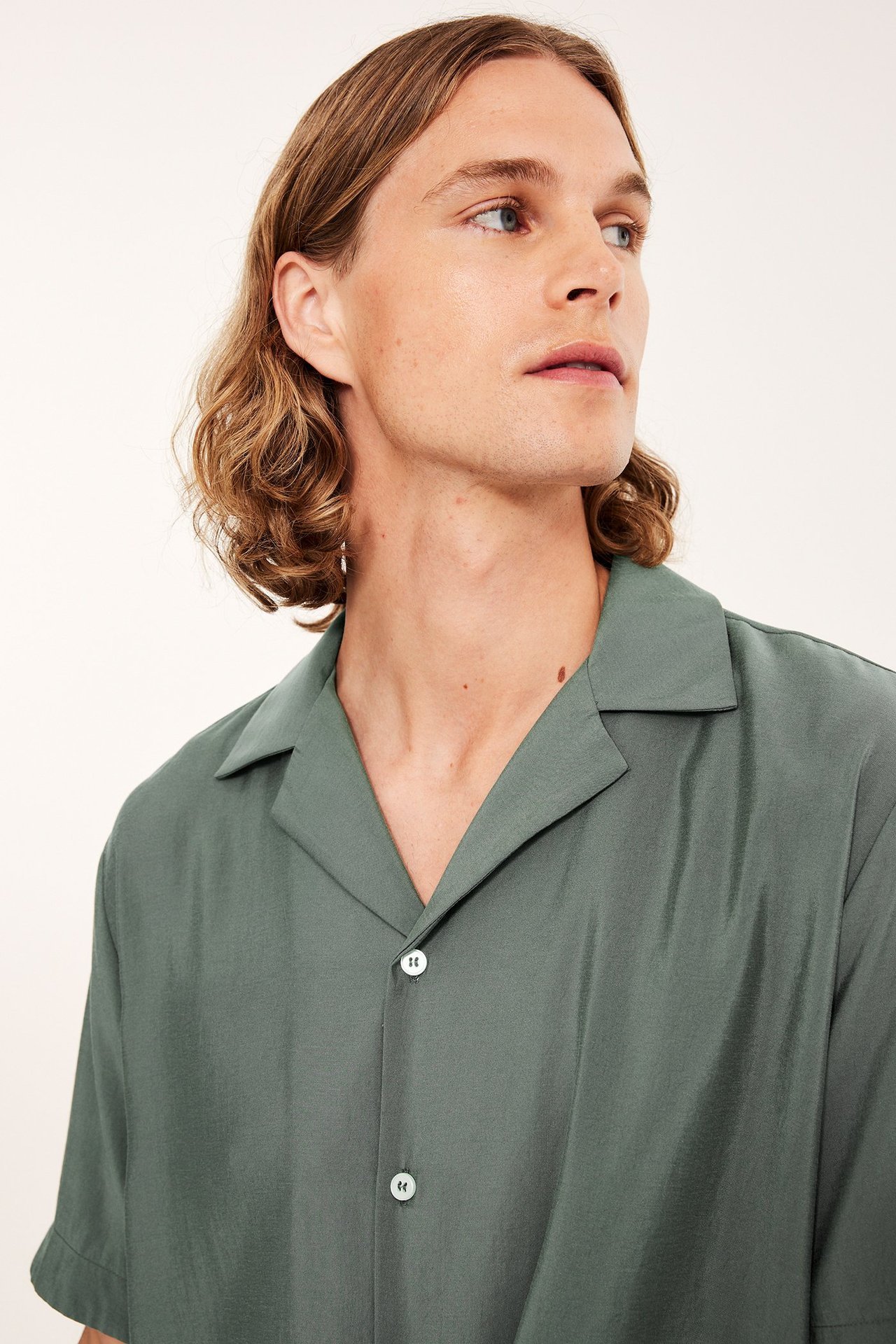 Lähikuva edestä miehestä yllään vihreä lyhythihainen resort-paita valkoisilla napeilla.