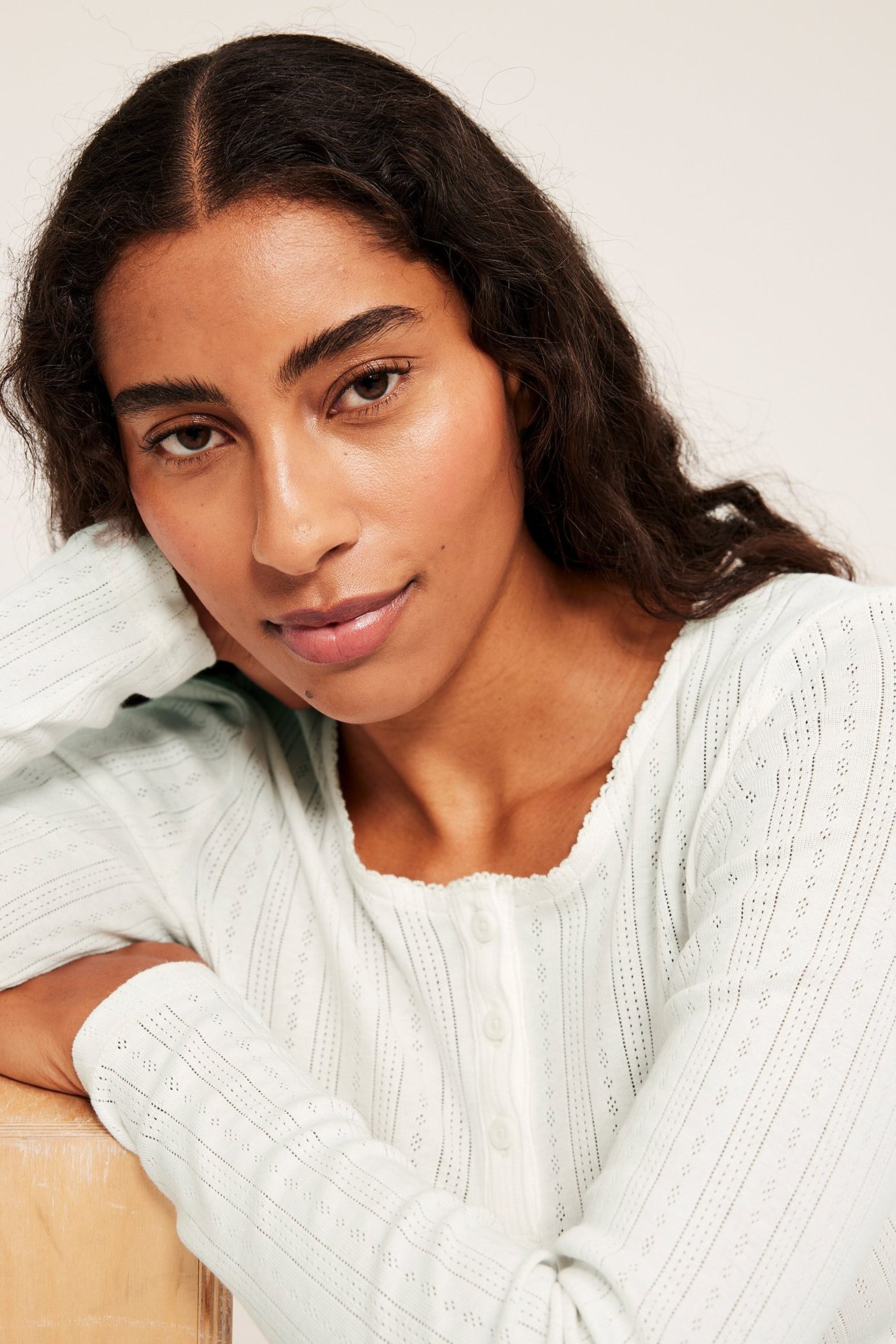 Nainen valkoisessa pitkähihaisessa pyjamapaidassa ribbiprinttiä puuvillaa, etukuvassa.