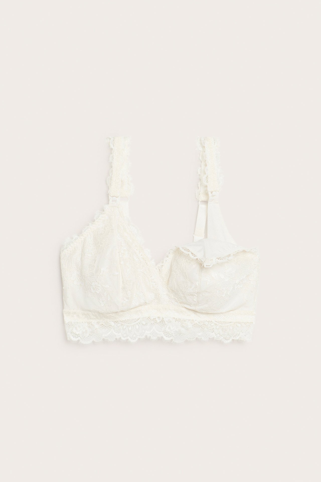 Frontvisning av en offwhite amme-BH i blonde med ammeklemmer, hekte- og øyelukking bak, justerbare stropper.