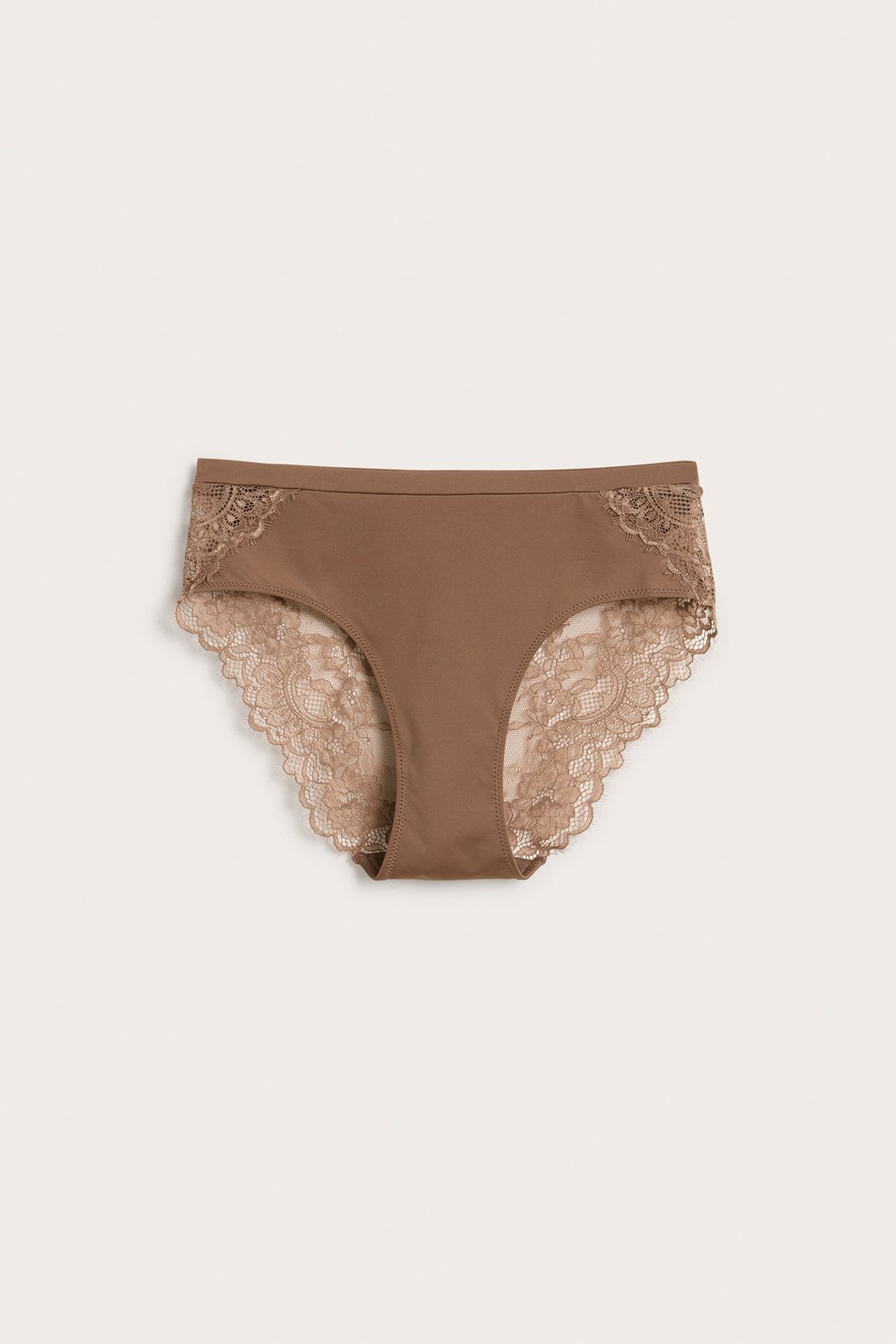 Frontbilde av beige mikrofibertruser for dame med blondedetaljer og bølgete kanter.