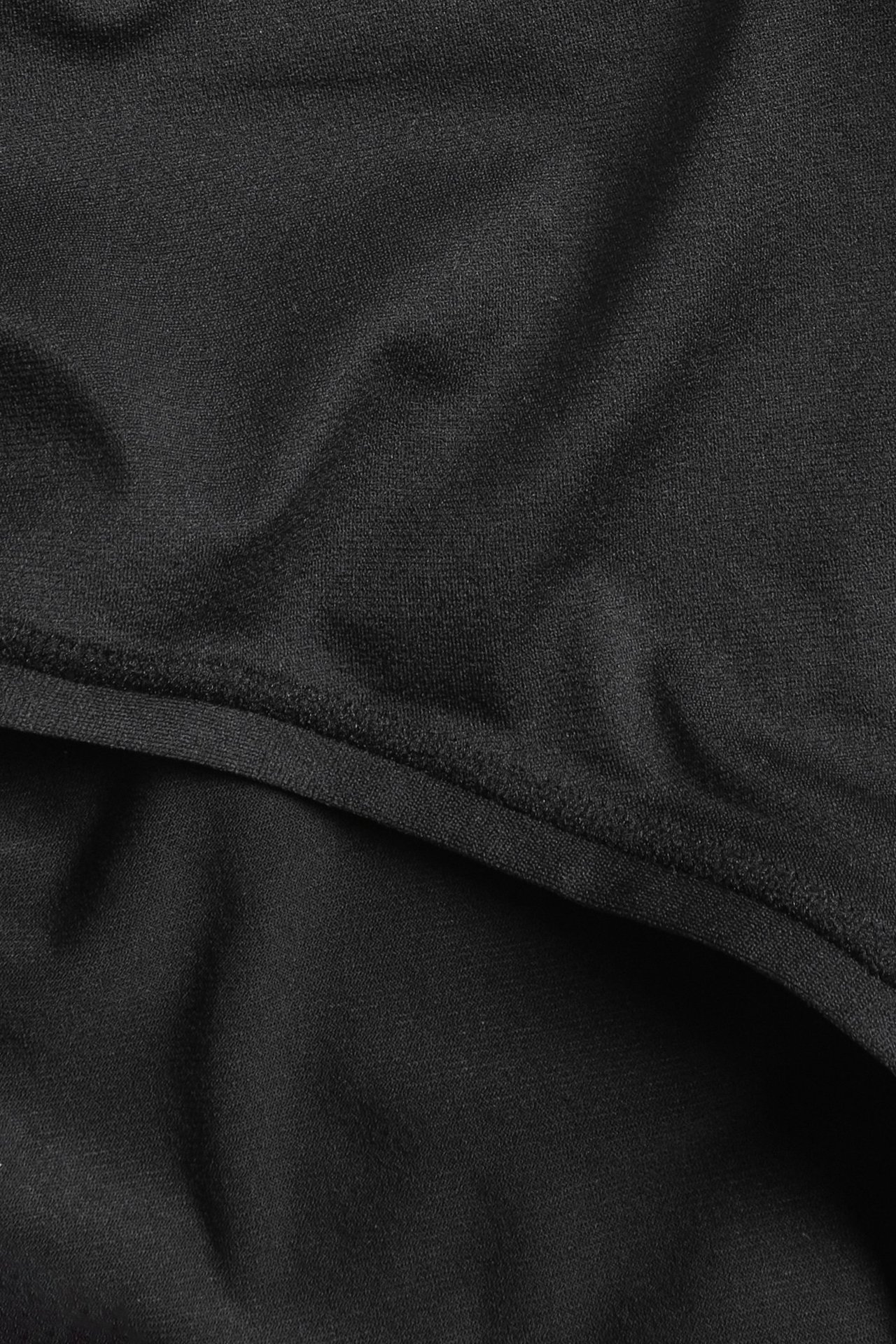 Zbliżenie na czarne, gładkie stringi z wysokim stanem i elastycznymi szwami, z miękkiego poliamidu z elastanem.