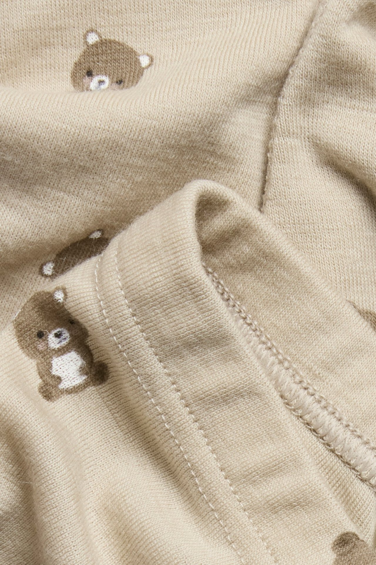 Zbliżenie beżowych legginsów z wełny merynosowej z brązowym wzorem niedźwiedzi.