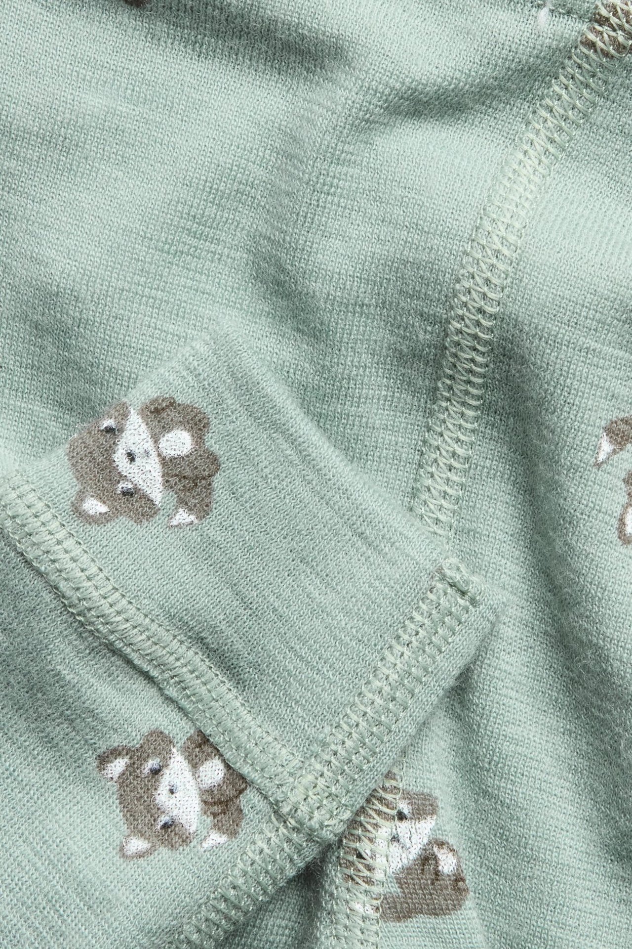 Zbliżenie na jasnozielone legginsy z wełny merynosów z brązowo-białym wzorem lisów.