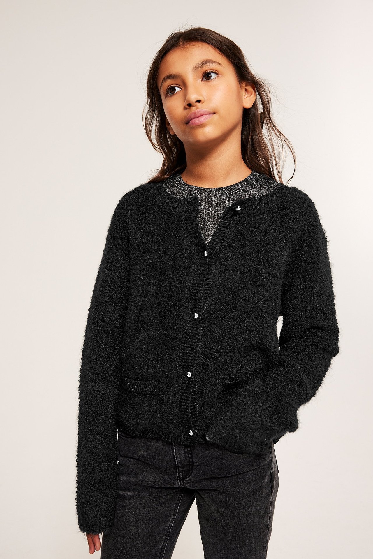 Lapsi yllään musta boucleneuletakki, metallinapit, taskut, harmaan topin ja tummien farkkujen kanssa.