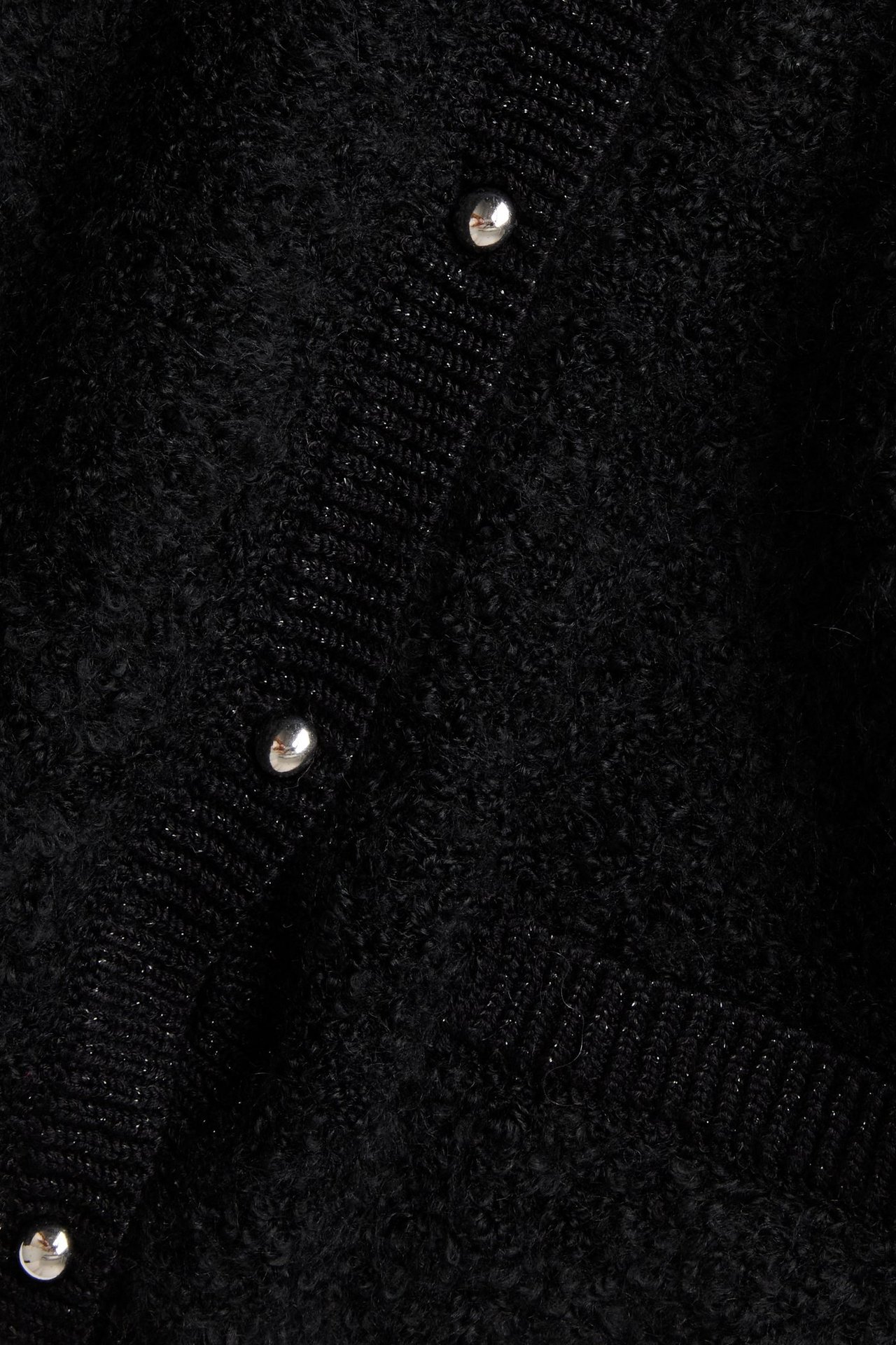 Zbliżenie czarnego swetra z bukle z metalowymi guzikami i delikatnym połyskiem lureksu.