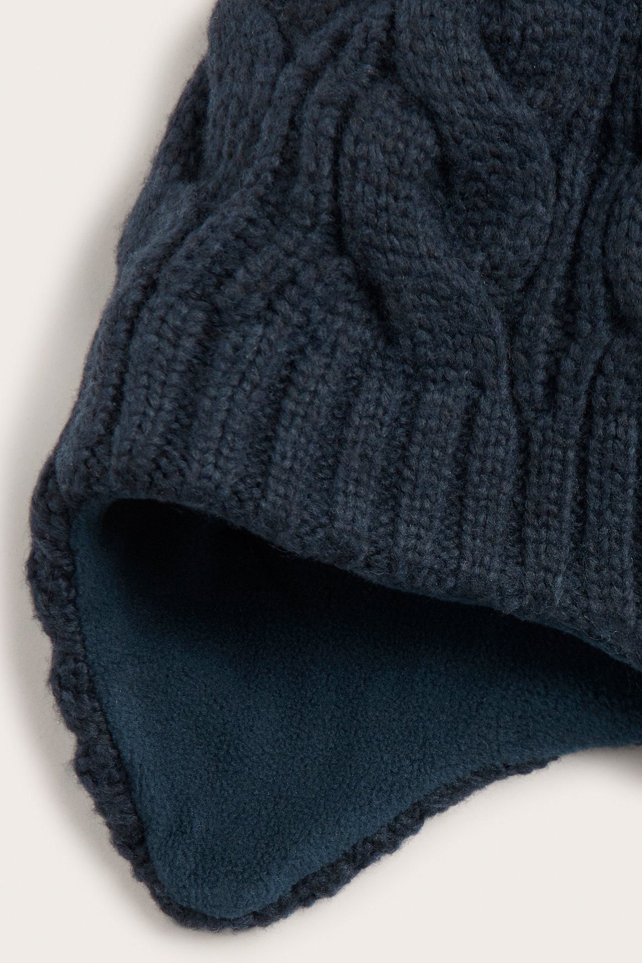 Lähikuva tummansinisestä palmikkoneulepipoista, jossa on pehmeä fleecevuori.