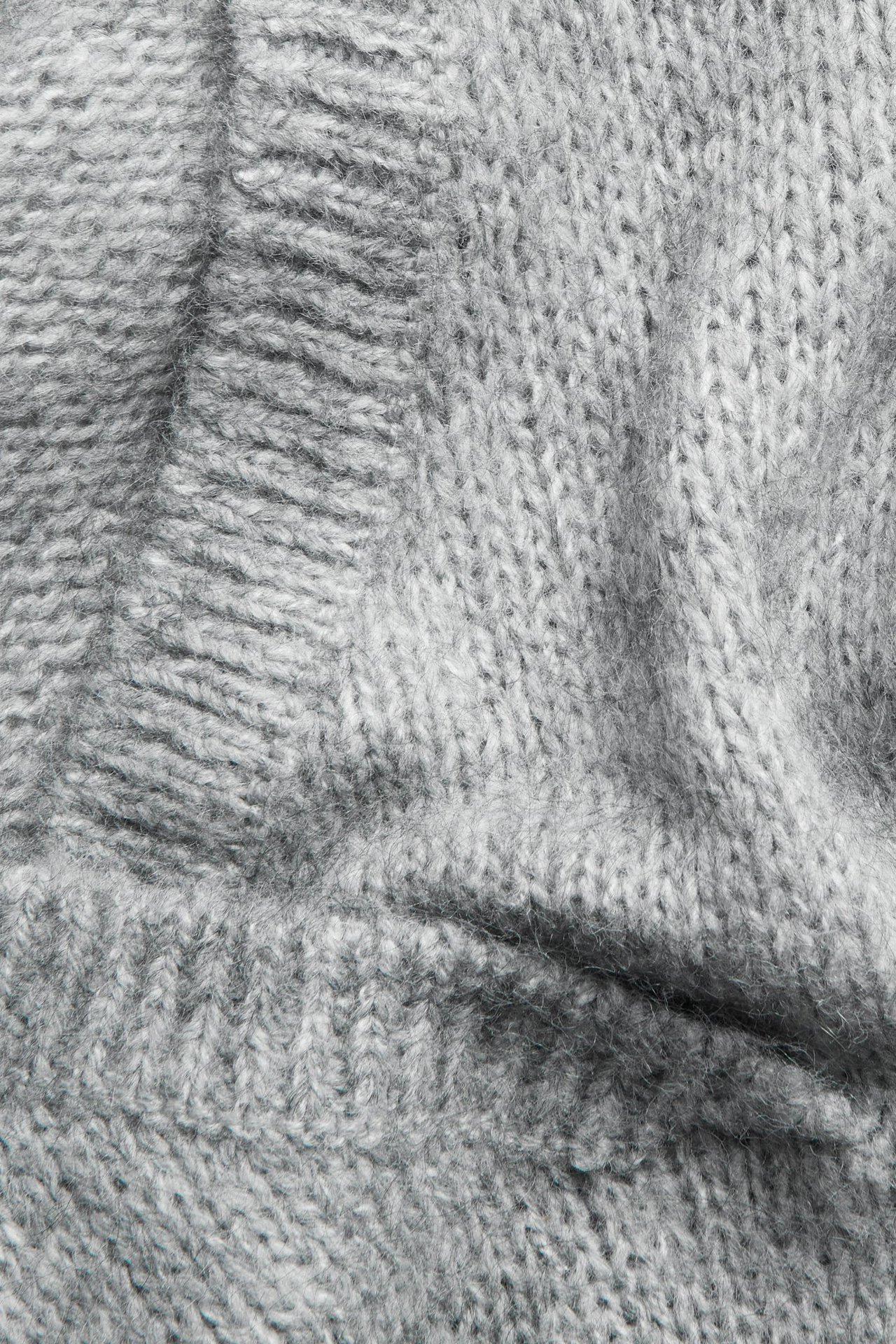 Zbliżenie szarego melanżowego swetra dzianinowego, ukazujące jego teksturę z mieszanki wełny i moheru.
