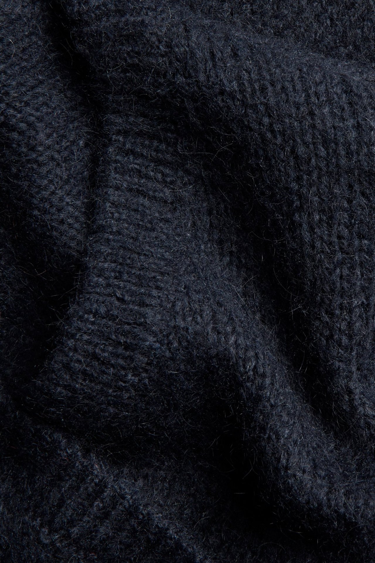 Zbliżenie na ciemnoniebieski, jednolity sweter z dzianiny z mieszanki wełny o puszystej fakturze.