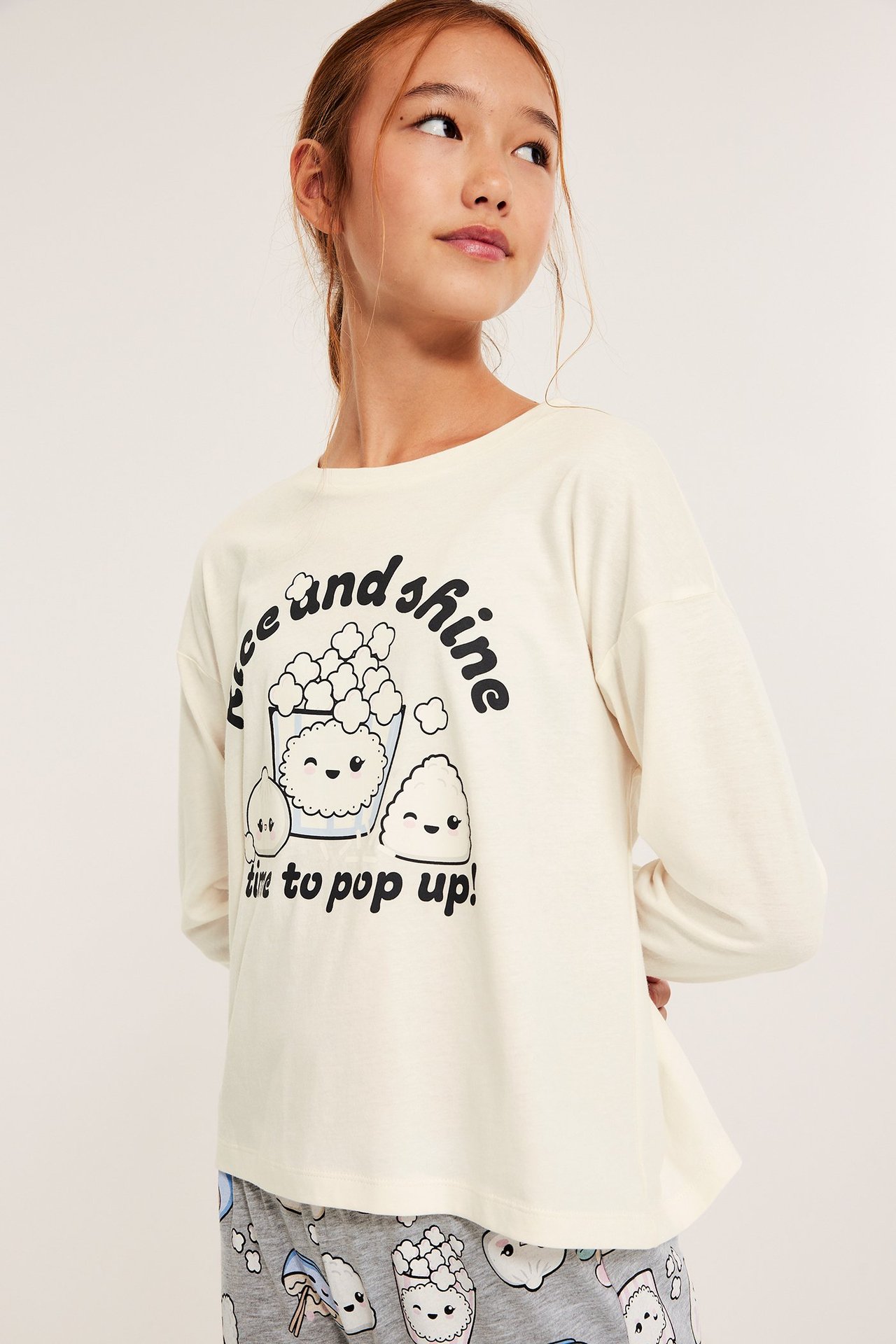 Kvinne i offwhite pysjamas med popcorn-trykk, frontvisning, nøytral bakgrunn.