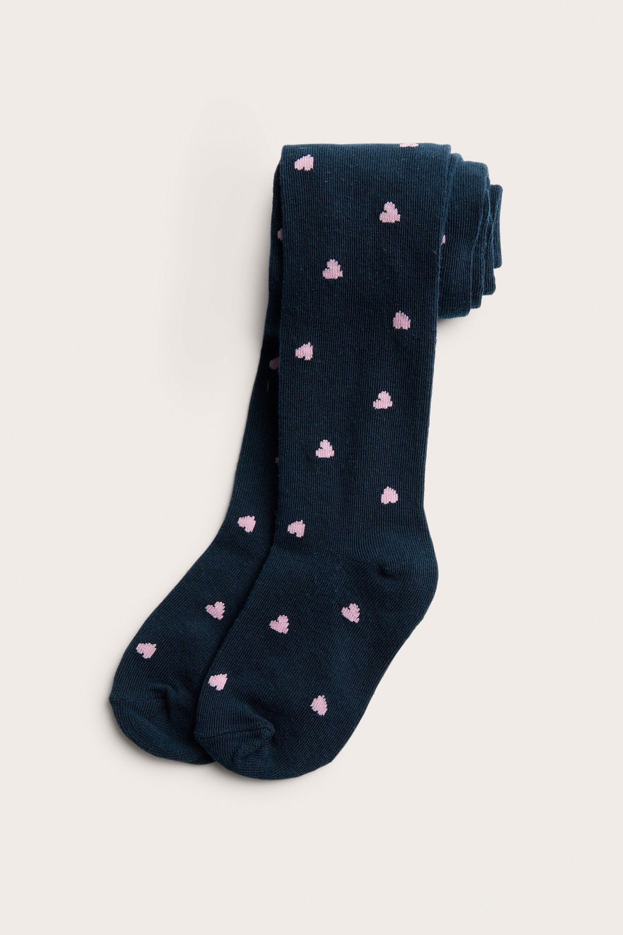 Ylhäältä kuvatut taitetut lasten tummansiniset sukkahousut vaaleanpunaisella sydänkuviolla.