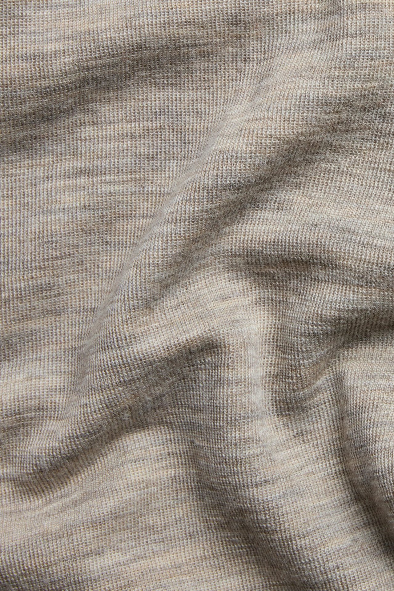 Zbliżenie na beżowy melanżowy materiał z wełny merynosów na spodnie, z prążkowaną fakturą.