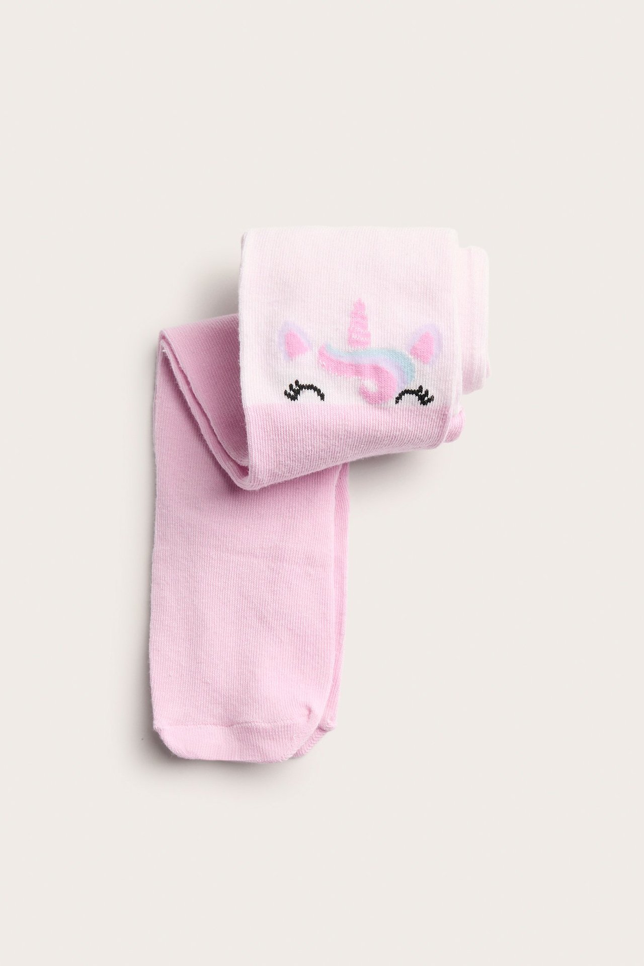 Ylhäältä kuvattu: kaksi paria taitettuja vaaleanpunaisia lasten sukkahousuja, toisessa yksisarviskuvio.