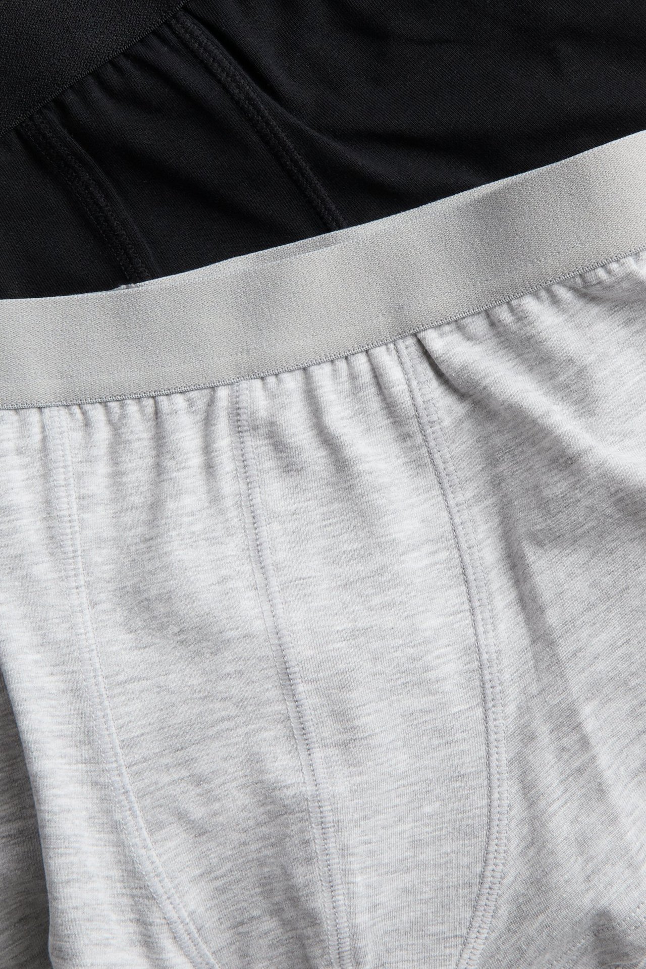 Zbliżenie na jasnoszare bokserki z elastycznym pasem i czarną parę z tyłu.