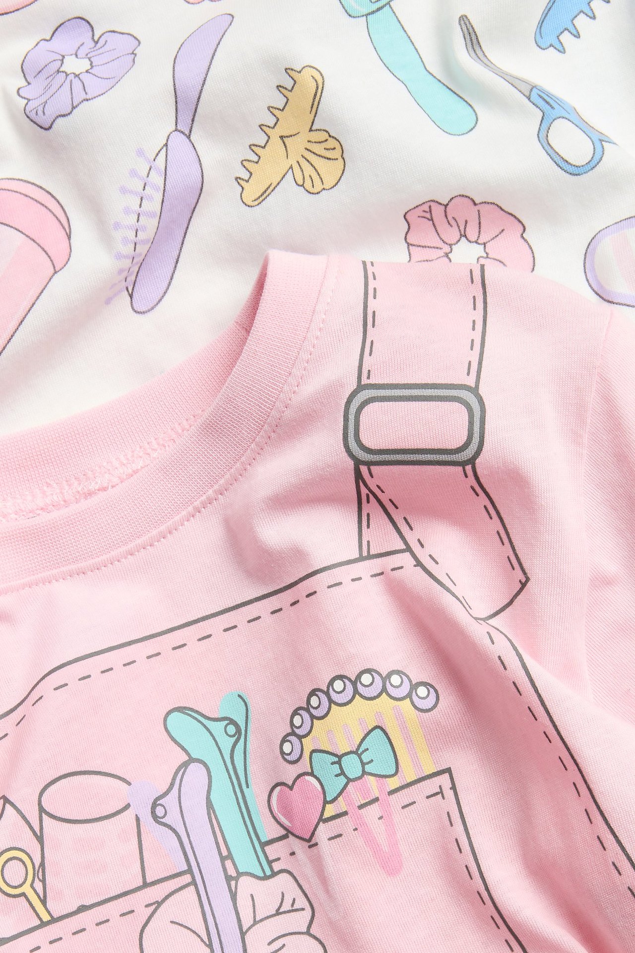 Zbliżenie różowej bawełnianej piżamy z wzorem narzędzi fryzjerskich i białej piżamy.