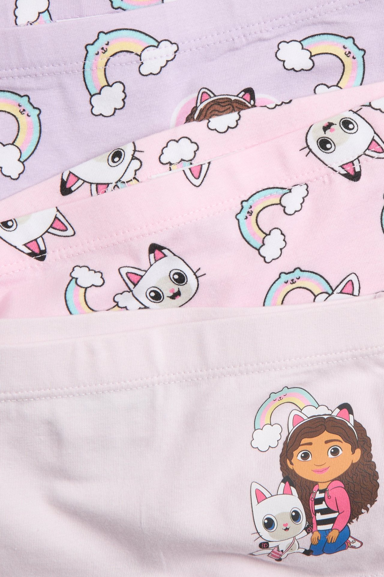 Zbliżenie na trzy złożone bokserki dziecięce w jasnym liliowym i różowym kolorze z motywem Gabby's Dollhouse.