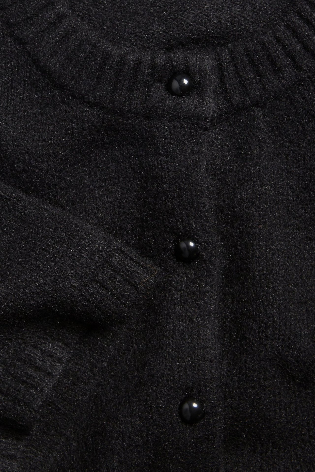 Zbliżenie z przodu na czarny melanżowy kardigan z krótkim rękawem i trzema błyszczącymi czarnymi guzikami.