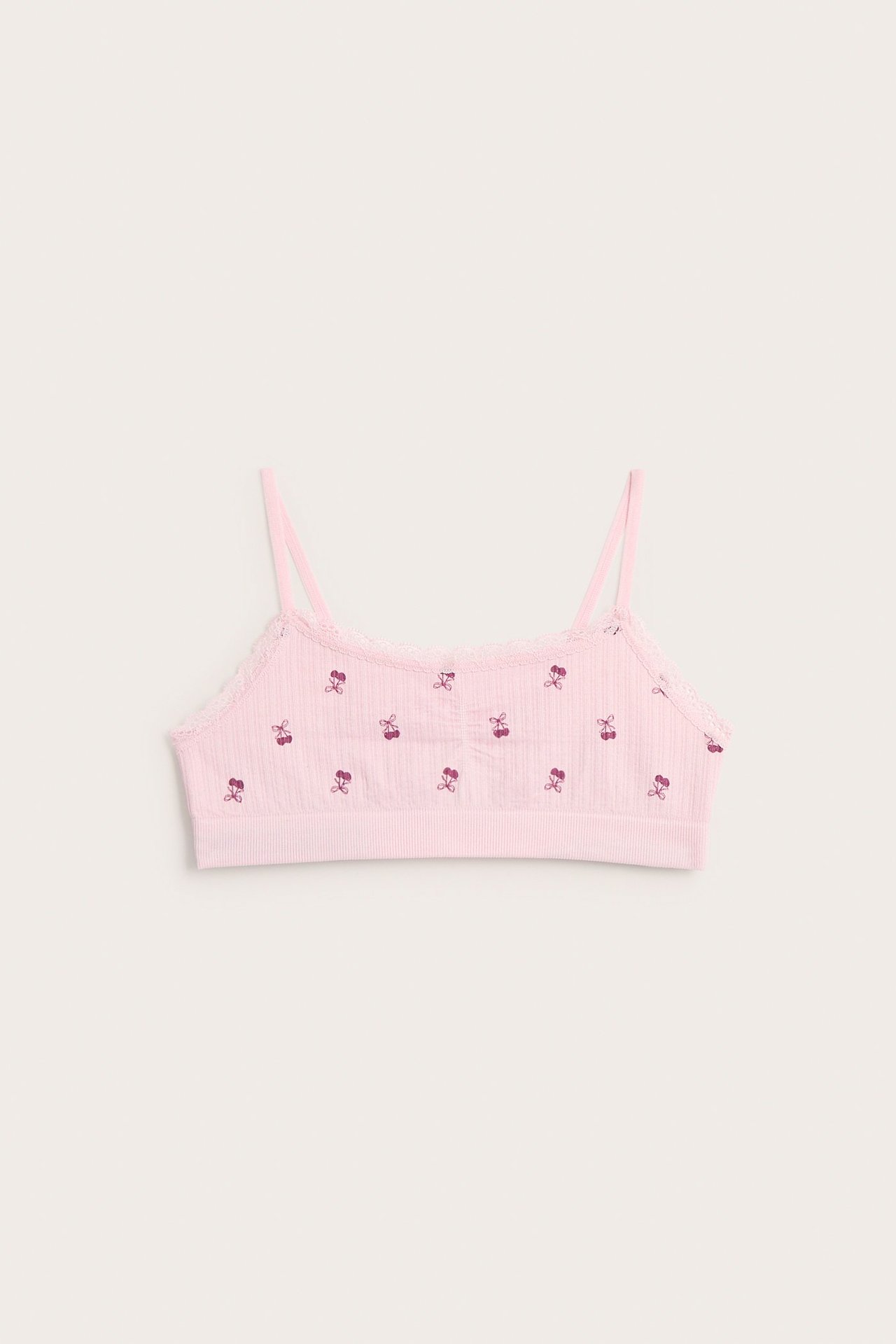 Widok z przodu różowego prążkowanego biustonosza z cienkimi ramiączkami, koronką i nadrukiem wiśni.