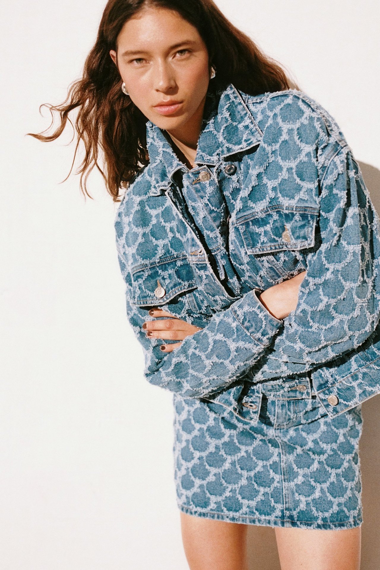 Frontvisning: Kvinne i kort denim jacquardjakke med lommer og matchende miniskjørt.