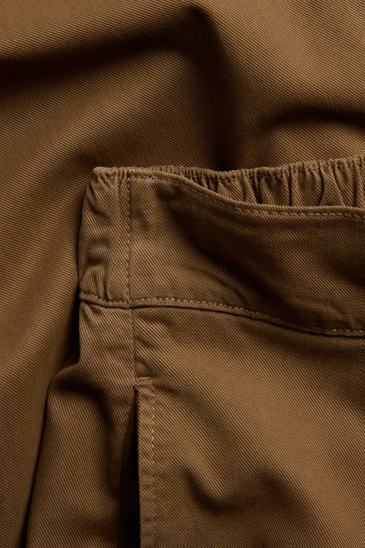 Zbliżenie brązowych spodni pull-on z bawełny/lyocellu z elastyczną talią i boczną kieszenią.