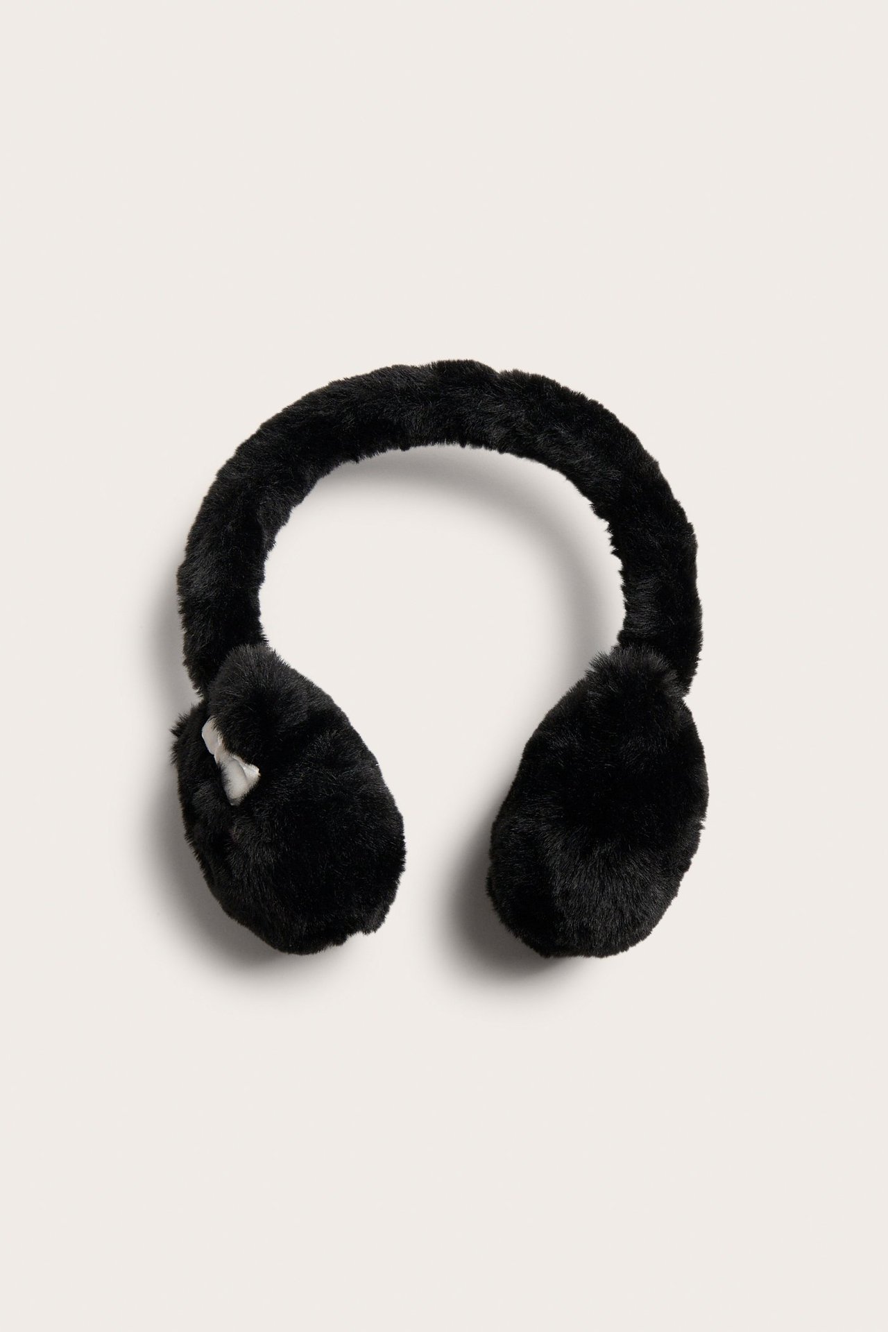 Widok z przodu czarnych, puszystych nauszników z małymi białymi uszami kota na każdej muszli.