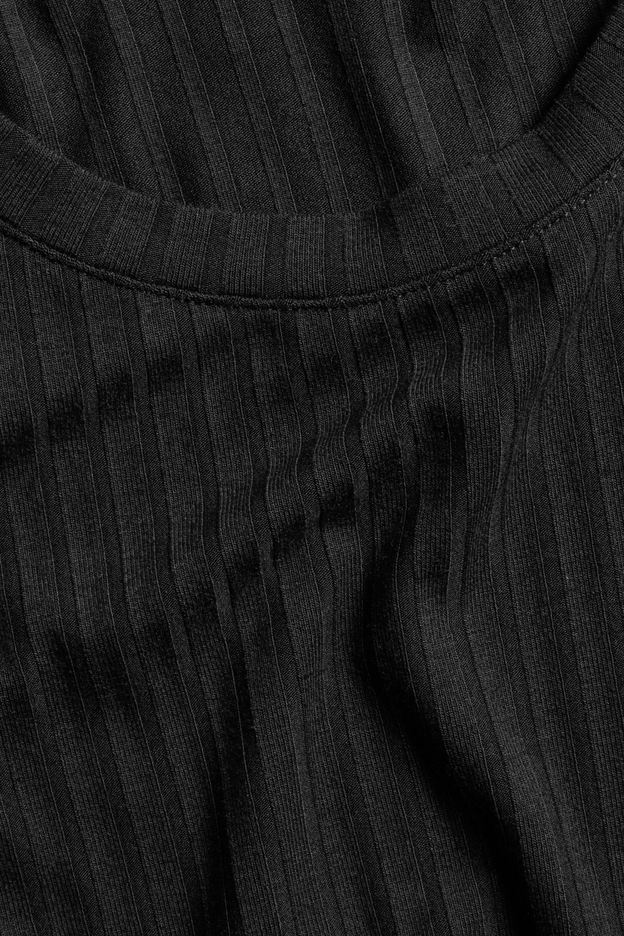 Zbliżenie czarnego prążkowanego topu z mieszanki wiskozy z okrągłym dekoltem.