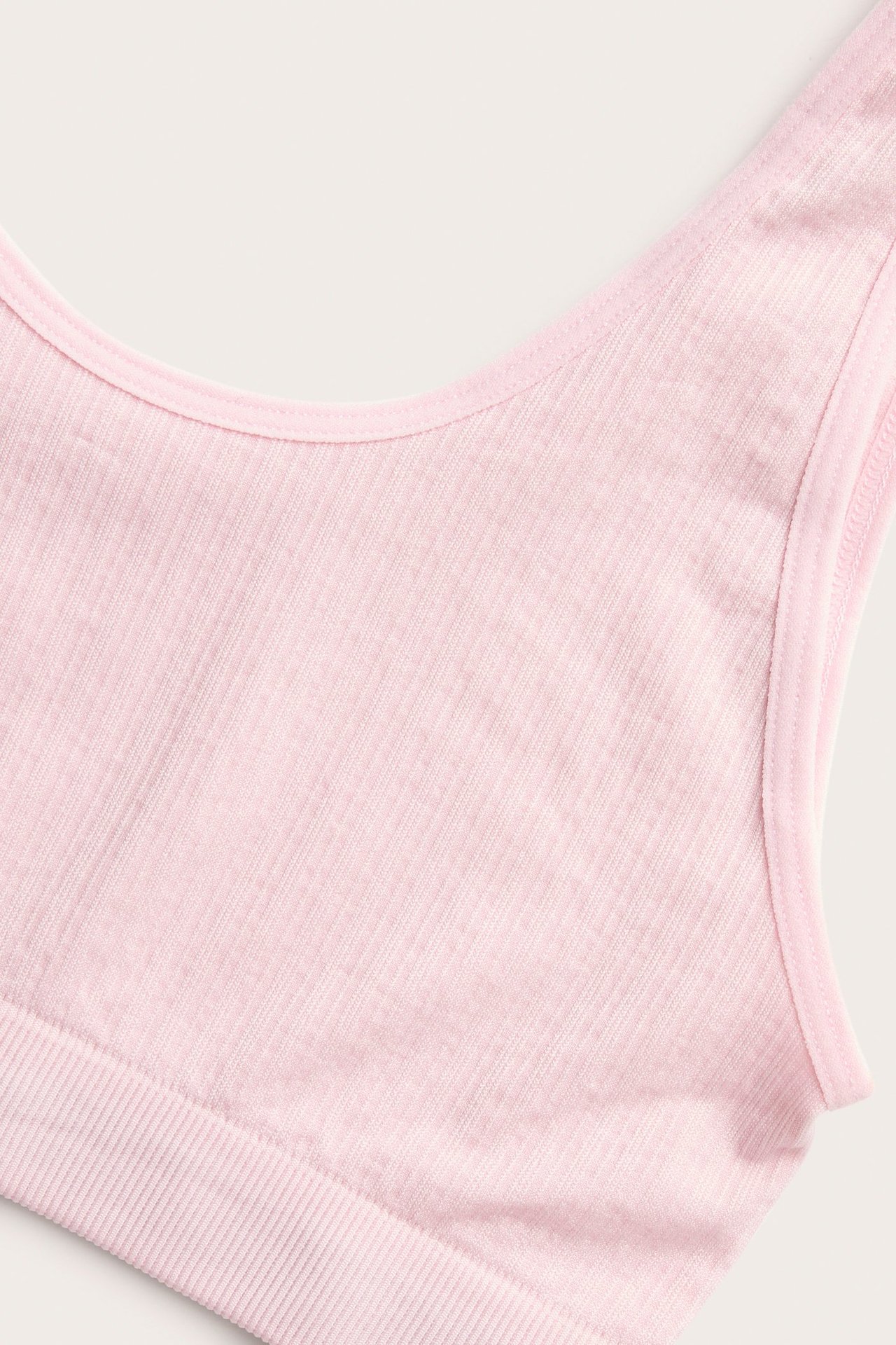 Nærbilde av en rosa ribbet topp med rund hals og bred skulderstropp.