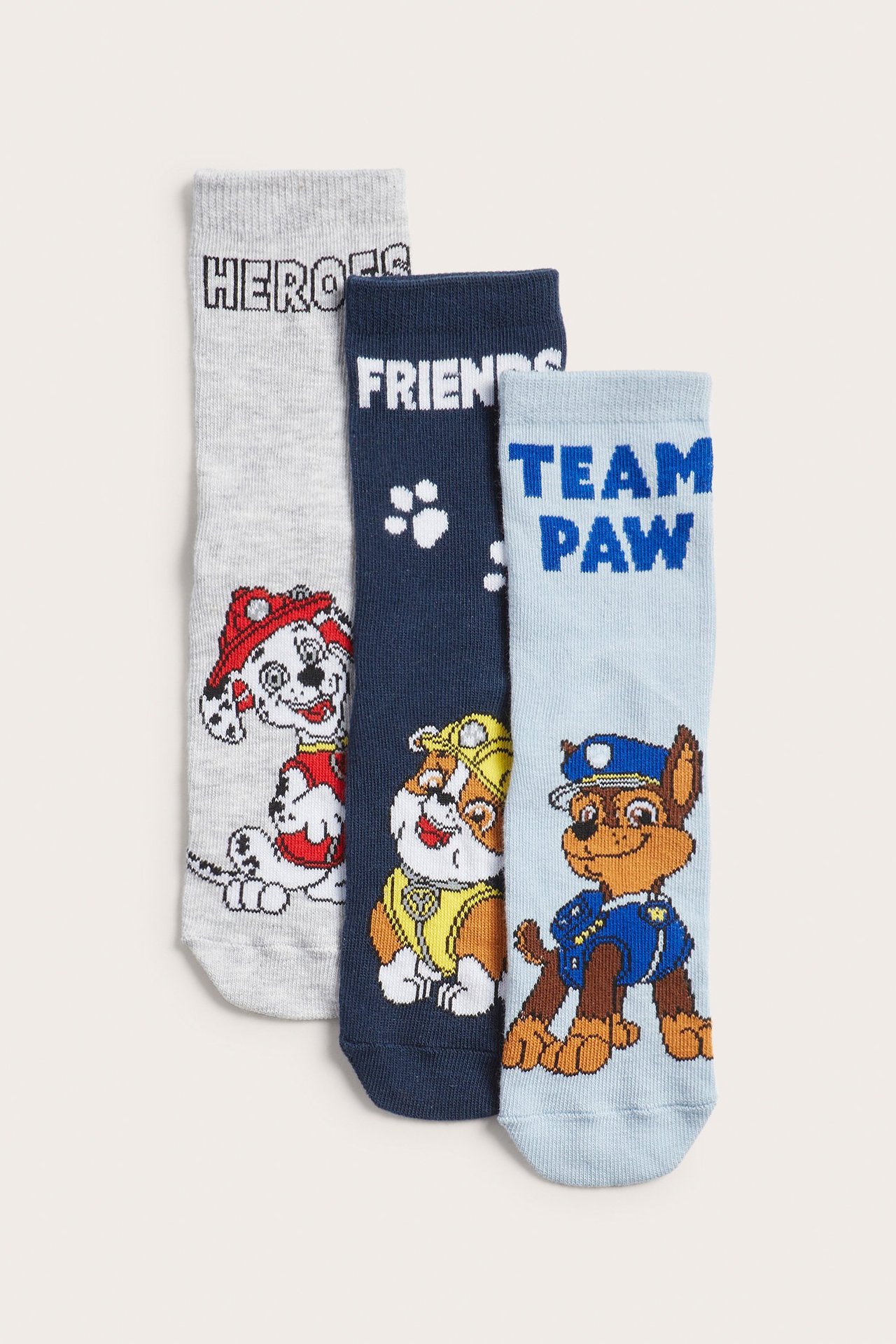 Widok z przodu trzech dziecięcych skarpetek Psi Patrol: jasnoniebieskich z Chasem, granatowych z Rubble i szarych z Marshallem.