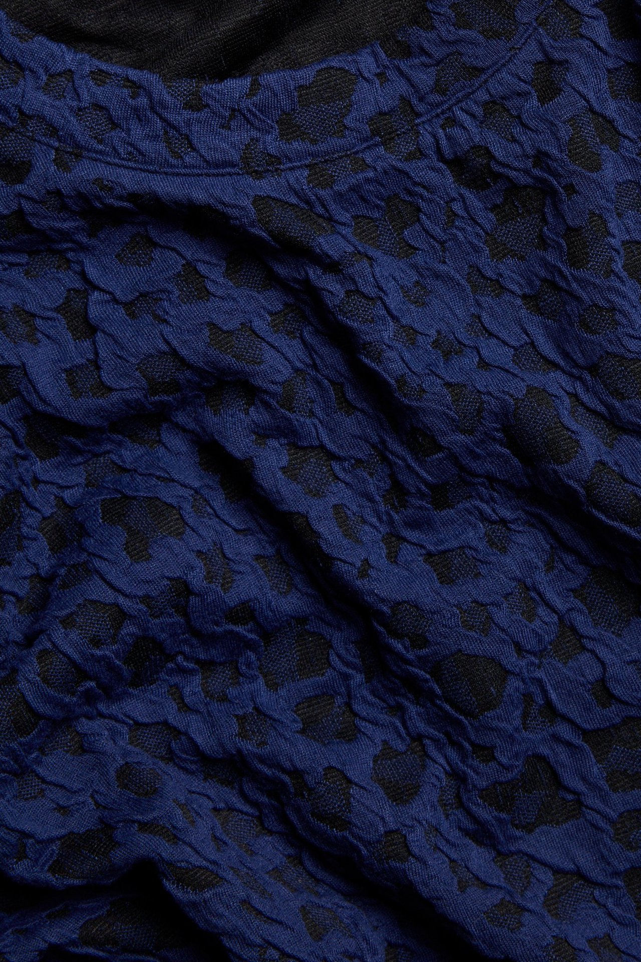Zbliżenie na ciemnoniebieski top żakardowy z teksturowanym zwierzęcym wzorem.