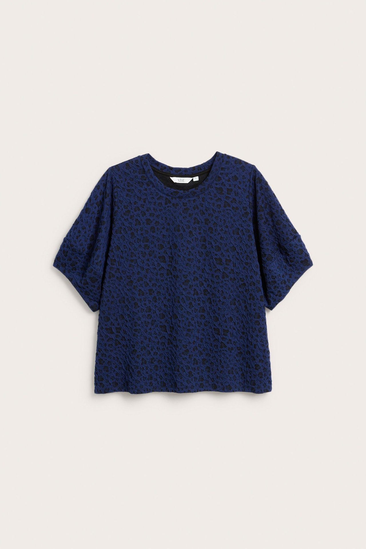 Widok z przodu ciemnoniebieskiego topu żakardowego w zwierzęcy wzór, z krótkimi rękawami i luźnym krojem.