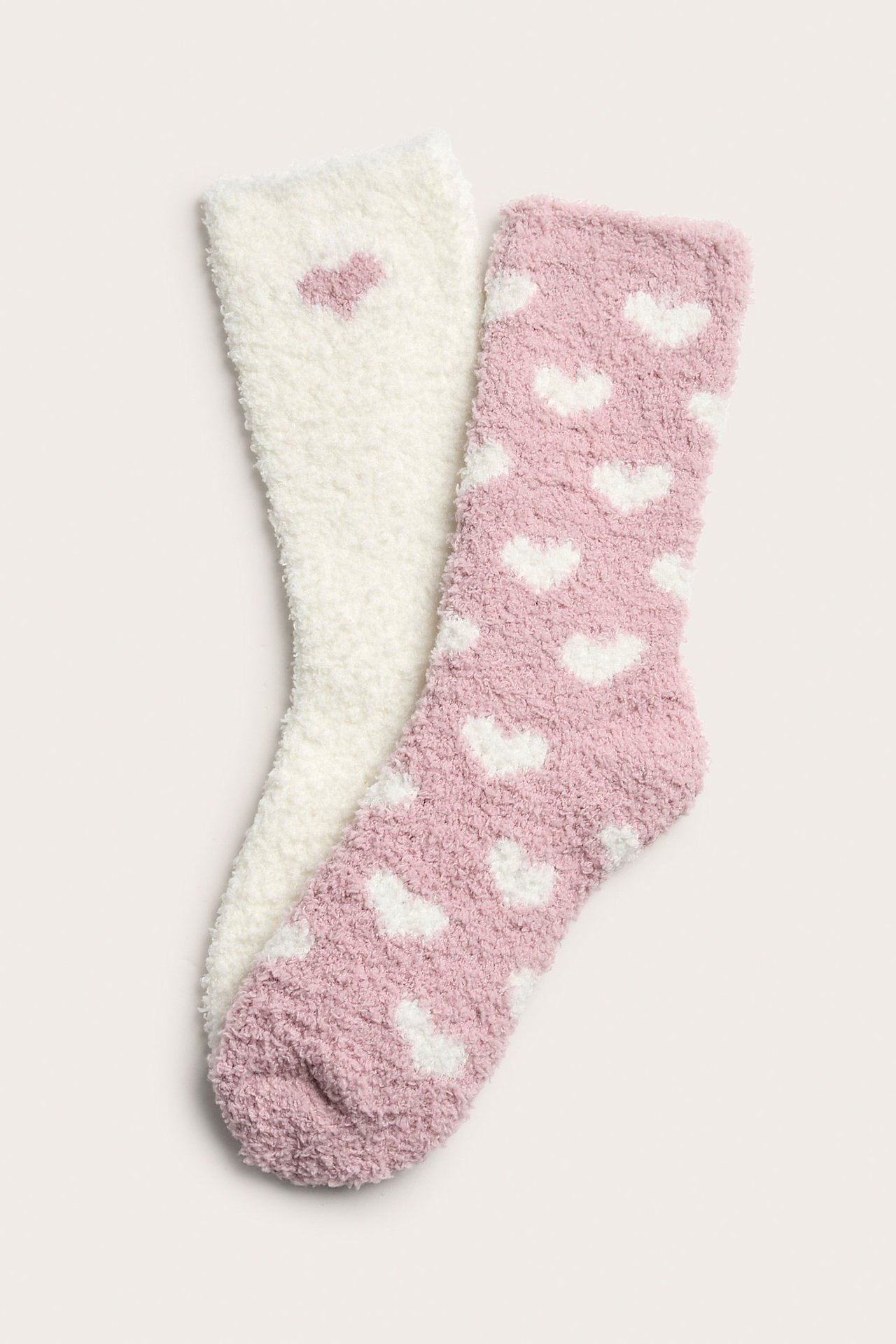 Widok z góry: dwie puszyste skarpetki, jasnoróżowe z białymi i kremowe z różowym sercem.