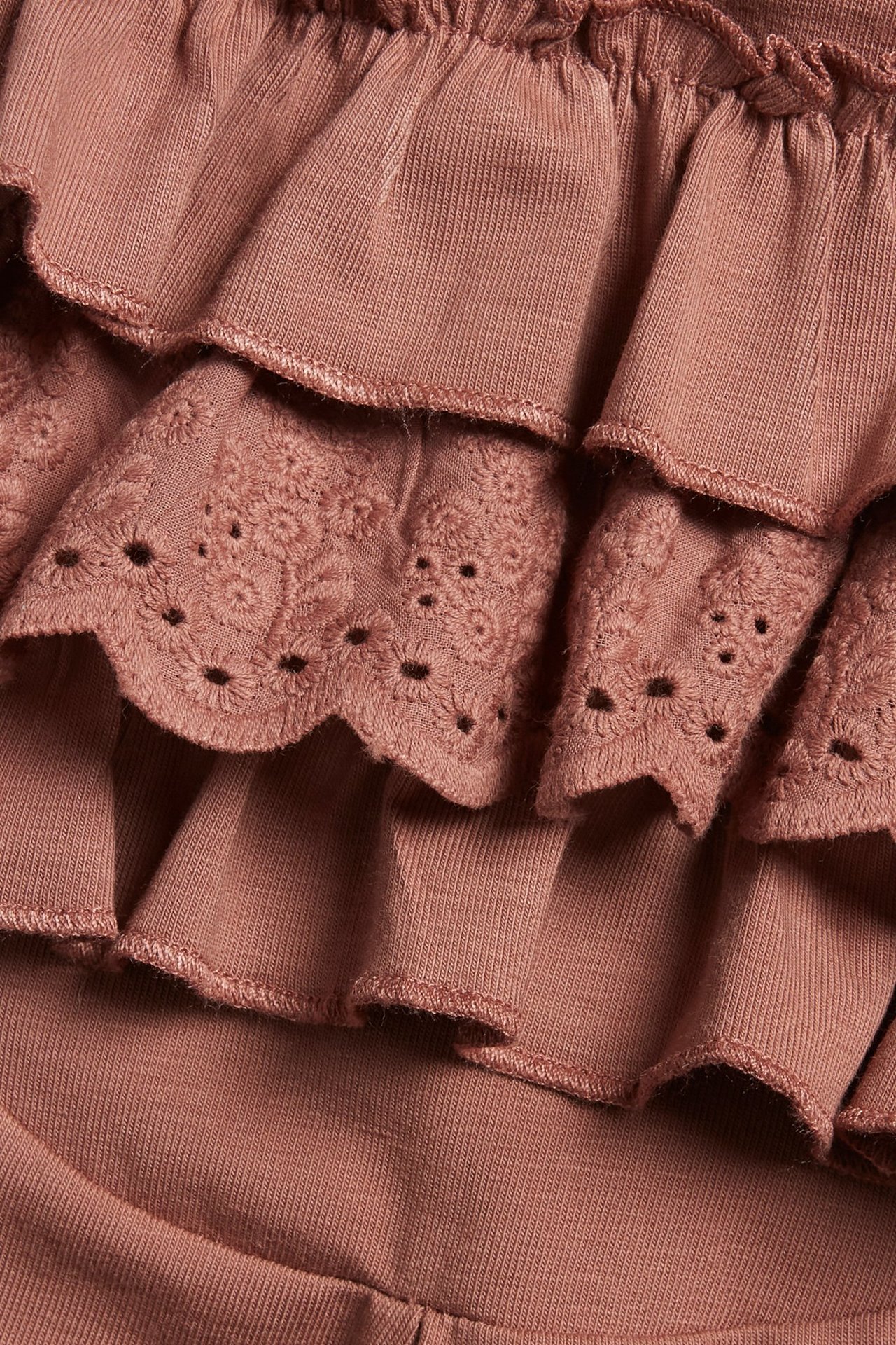 Widok z tyłu różowych bawełnianych legginsów z falbankami i koronką angielską.