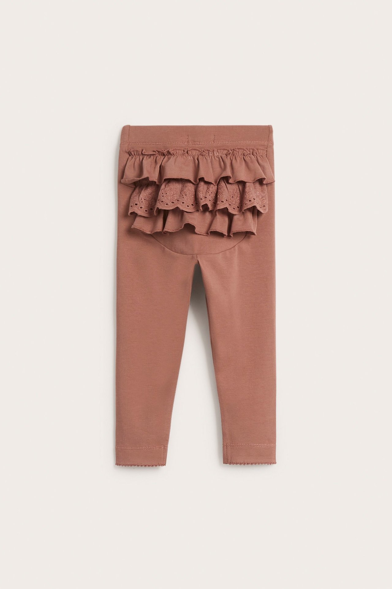 Ryggvy av rosa baby-leggings med lager av volanger och en spetsdetalj baktill.