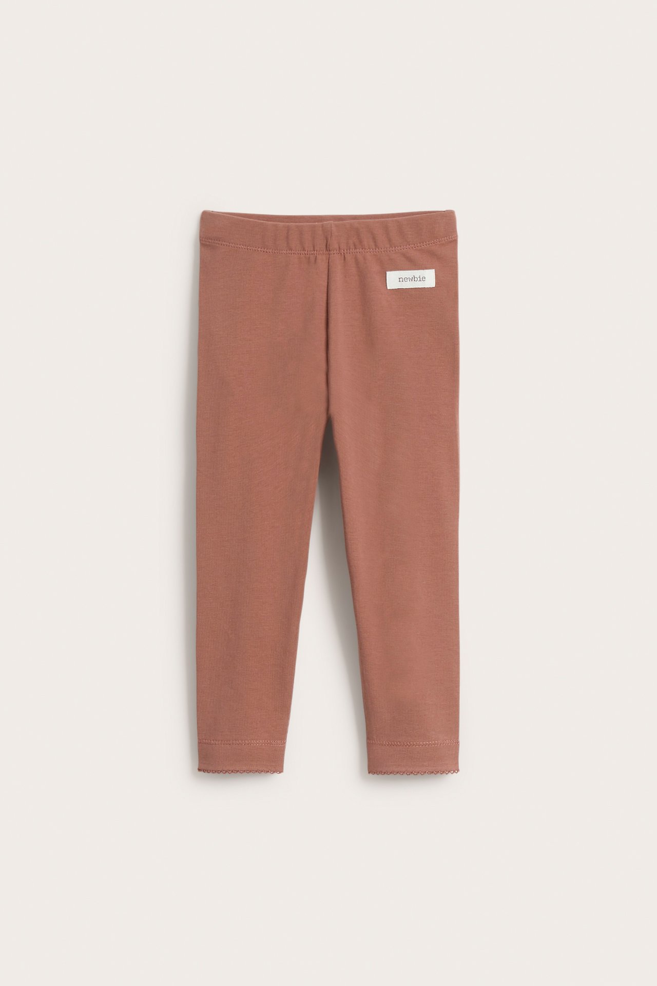 Frontvisning av rosa barneleggings med elastisk midje og bølget blondekant ved anklene.