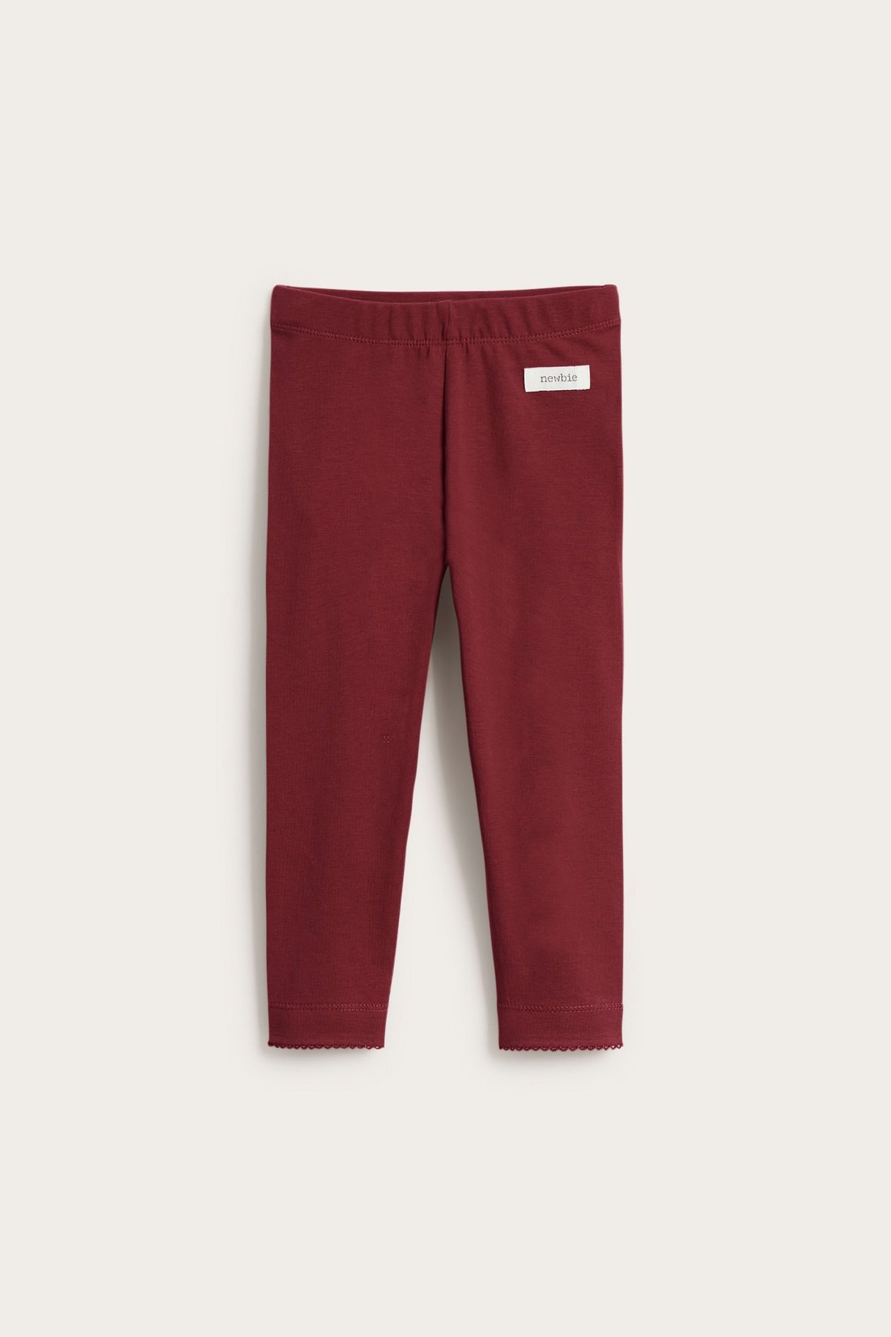 Frontbilde av mørkerøde barne-leggings med elastisk midje og bølget kant ved anklene.
