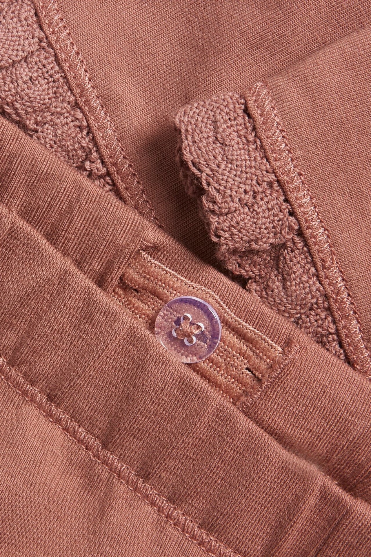 Lähikuva tummanpunaisista lasten leggingseistä, joissa pitsiröyhelö ja säädettävä nappivyötärö.