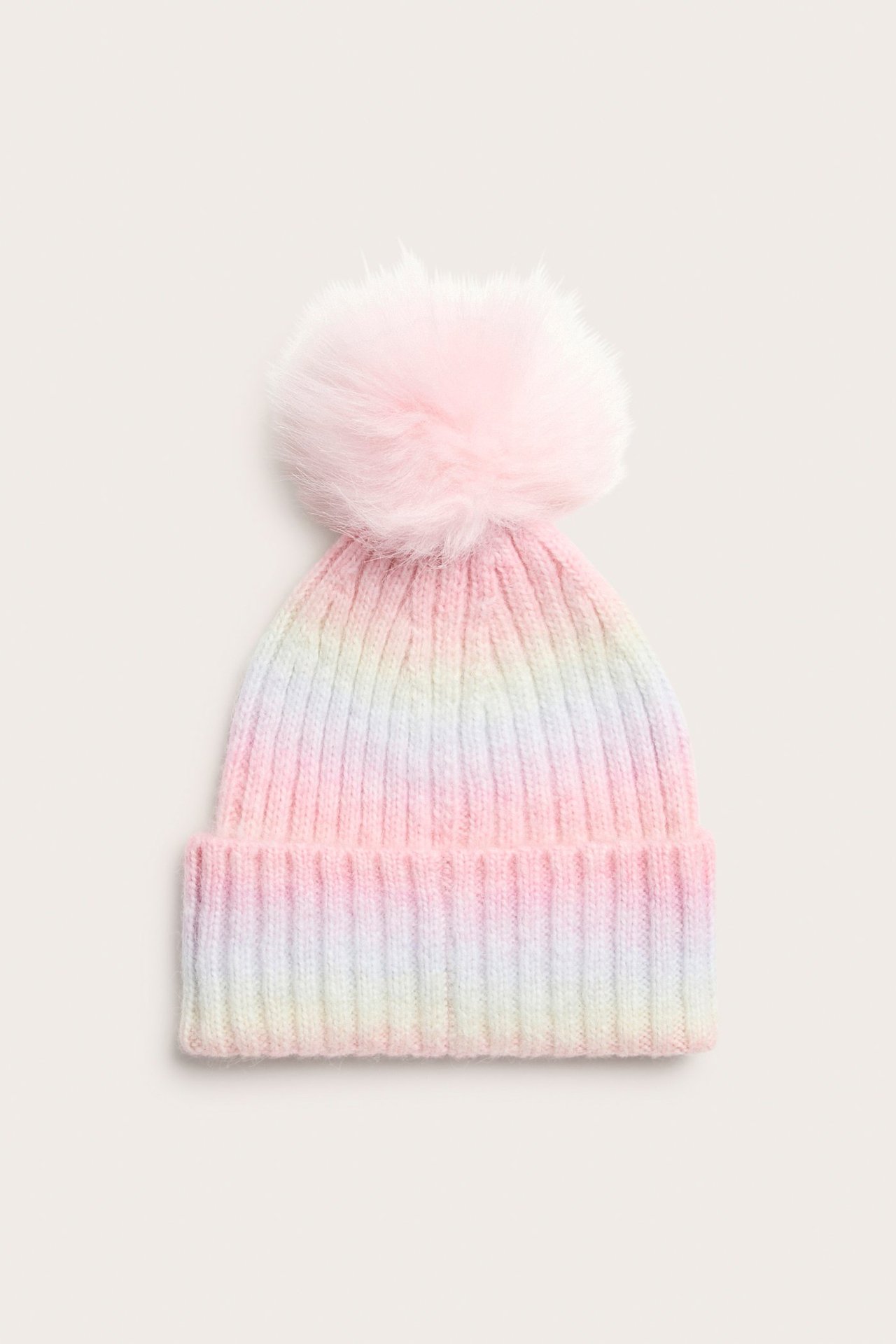 Edestä, lasten ribbineulepipo pastellinvärisellä sateenkaarikuviolla ja vaaleanpunaisella tupsulla.