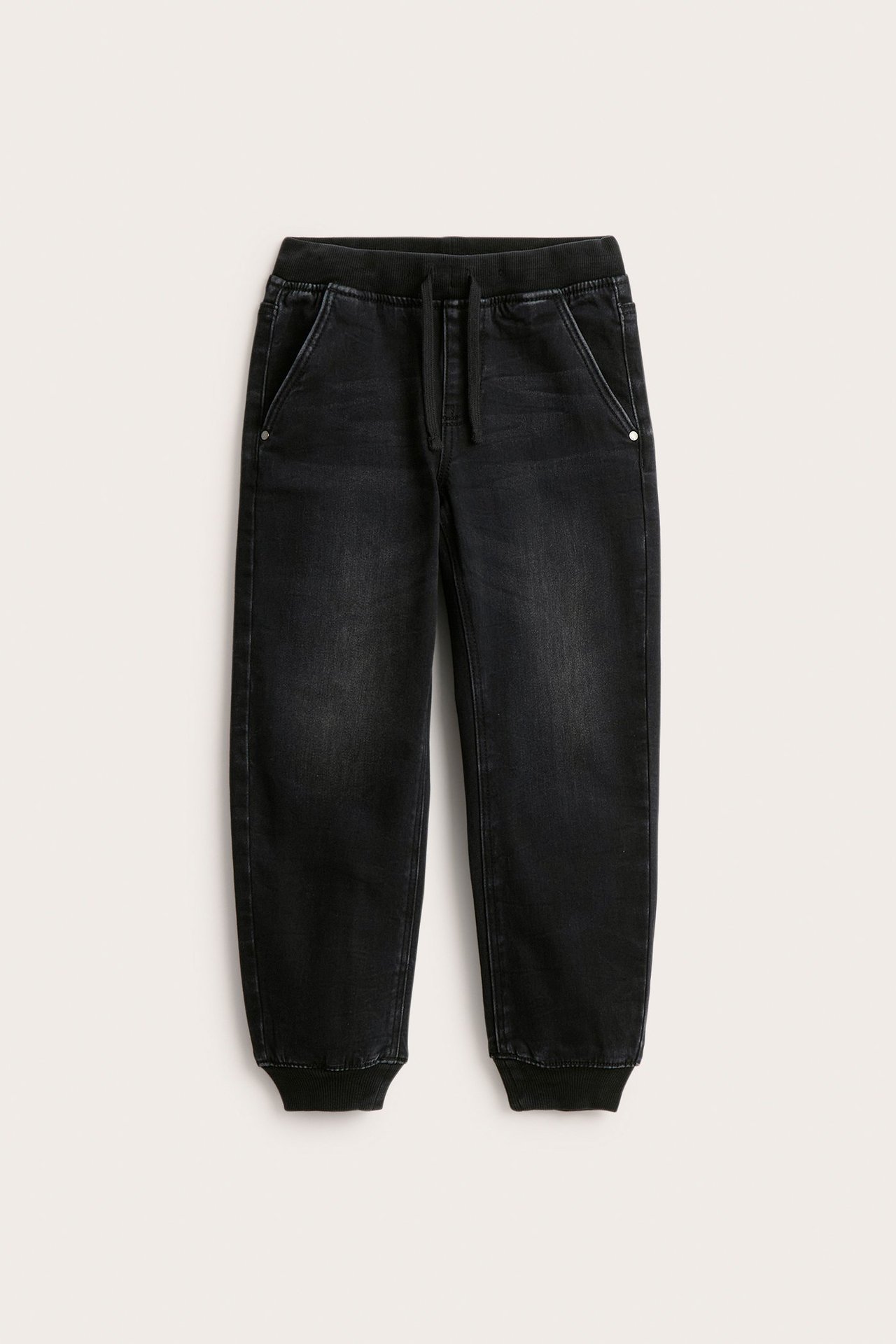 Edestä näkymä lasten mustista rentoista denim-joggerfarkuista, joissa ribbivyötärö ja resorit.