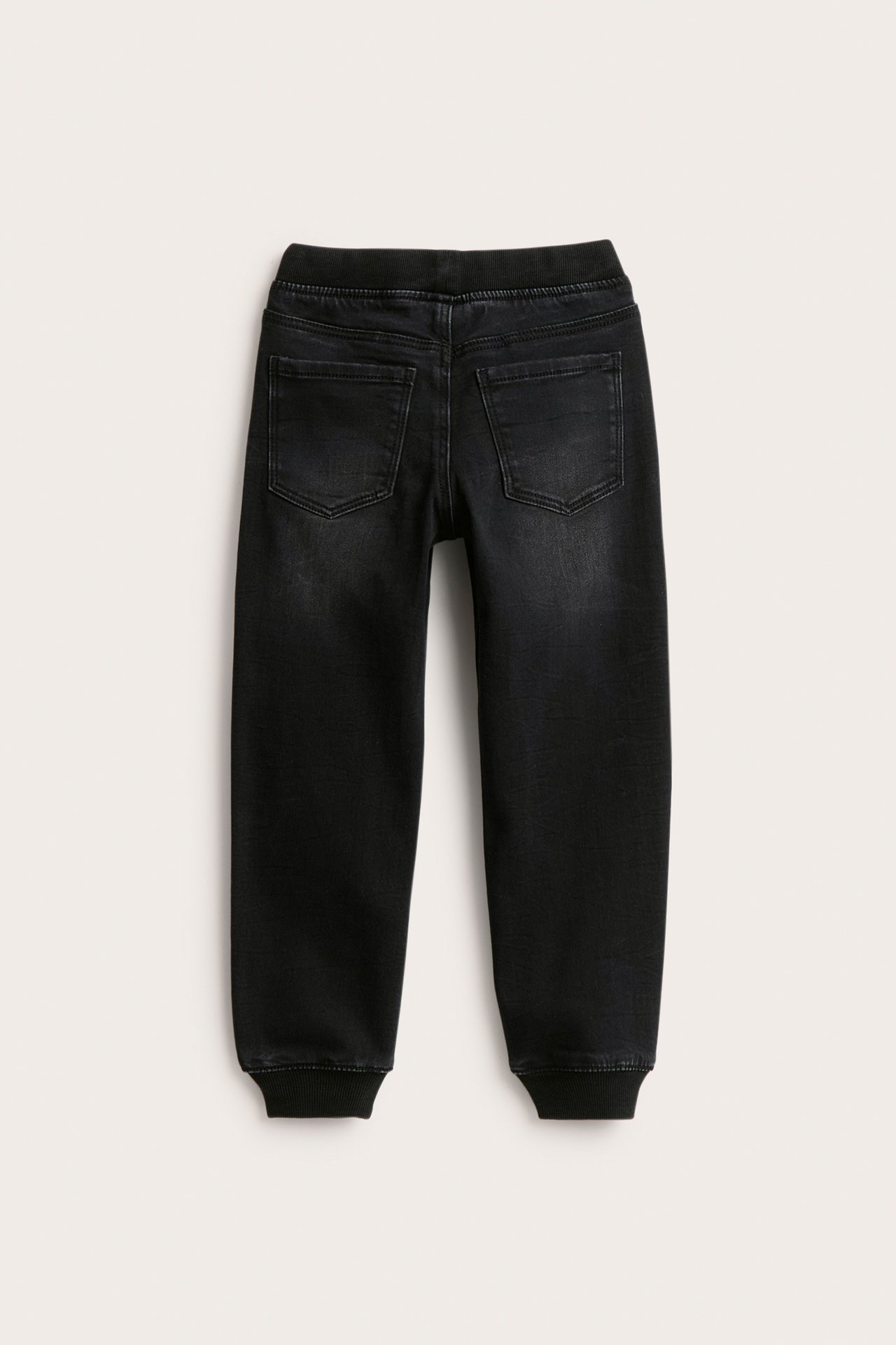 Bakifrån: svarta joggerjeans i denim för barn med ribbade muddar och resår i midjan.