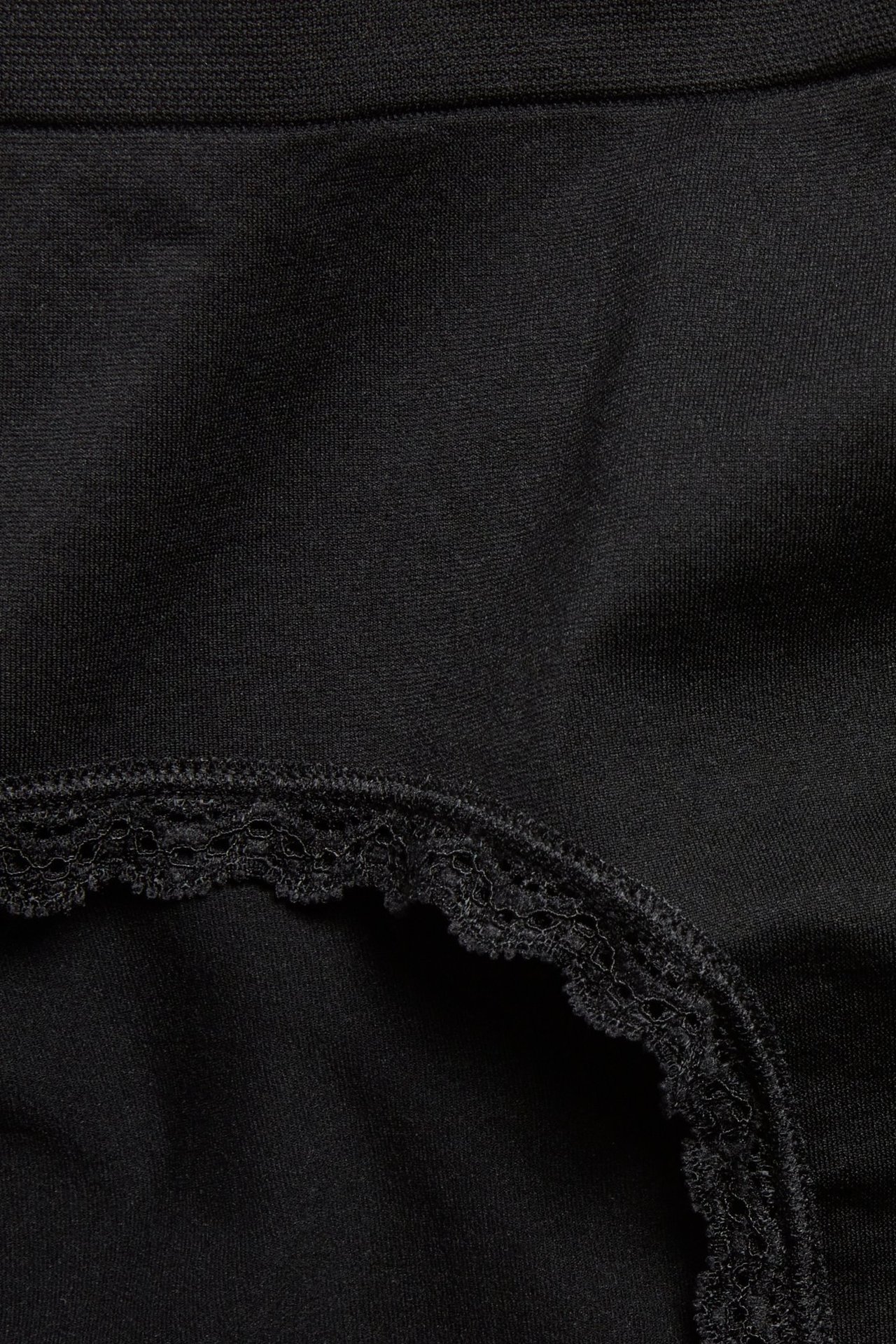 Zbliżenie na czarne, bezszwowe figi typu hipster z delikatną koronkową krawędzią.