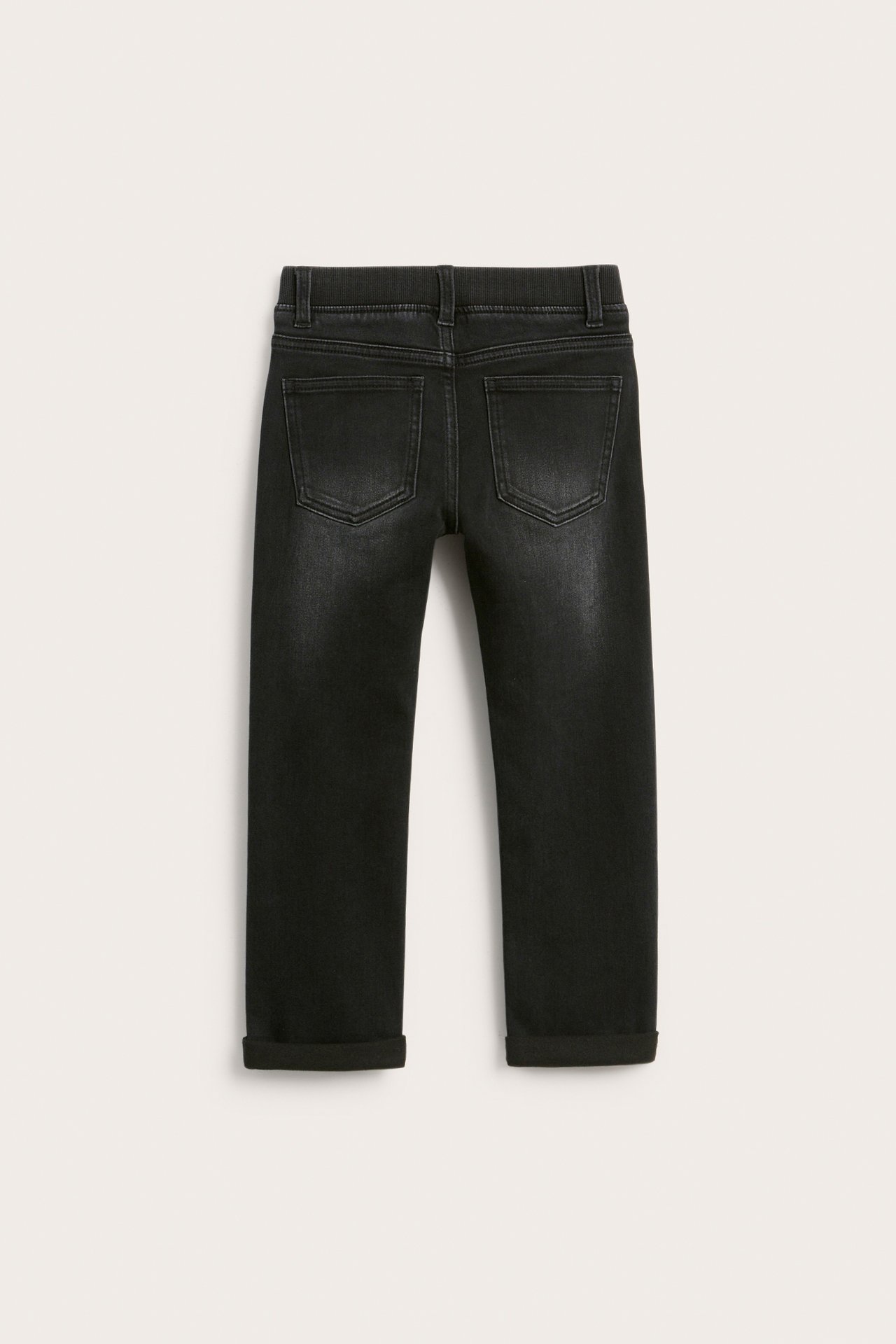 Bakifrån av svarta raka jeans i denim för barn med uppvikta benslut och bakfickor.