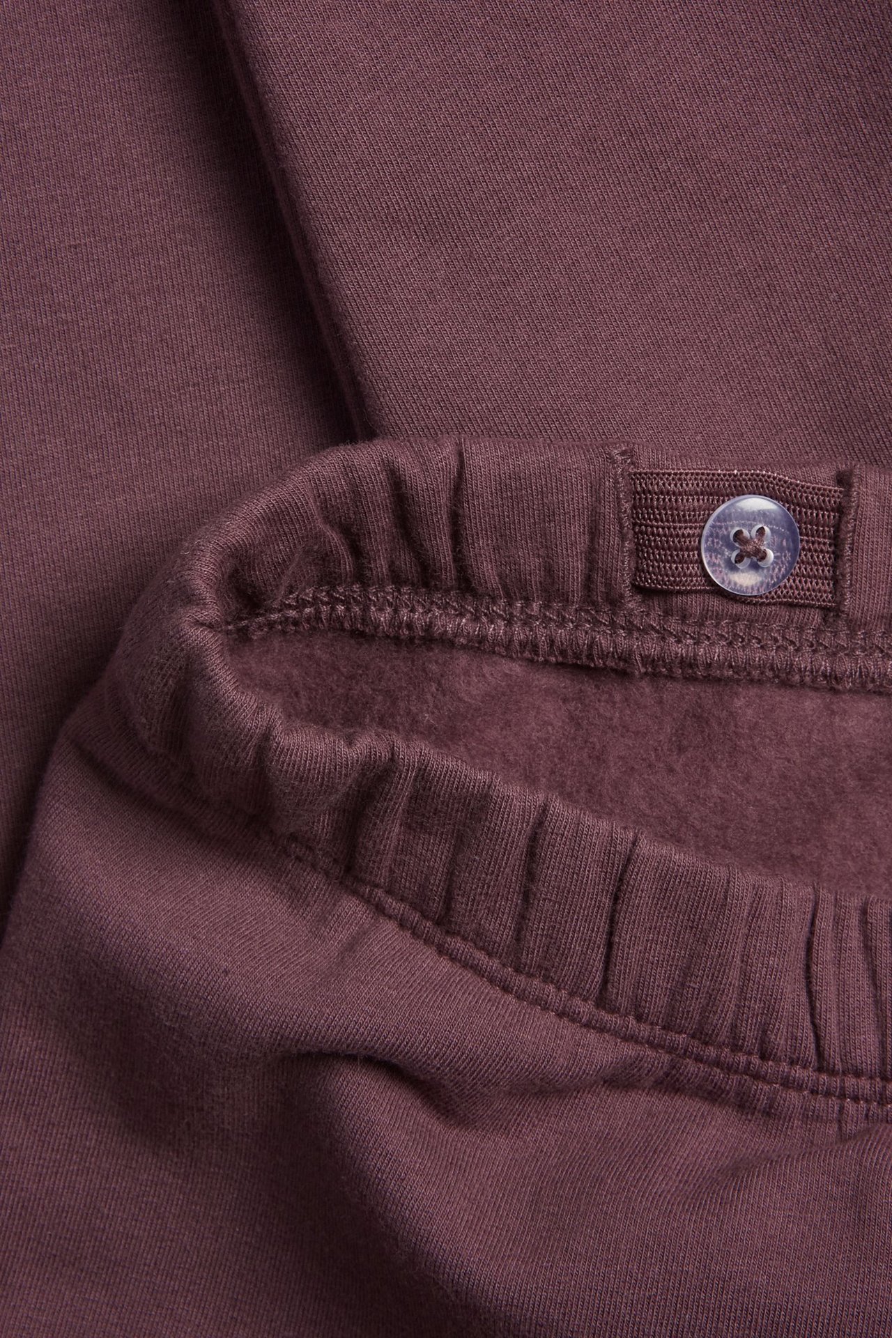 Lähikuva lilaista puuvillaleggingsistä, joissa säädettävä kuminauhavyötärö ja harjattu sisäpuoli.