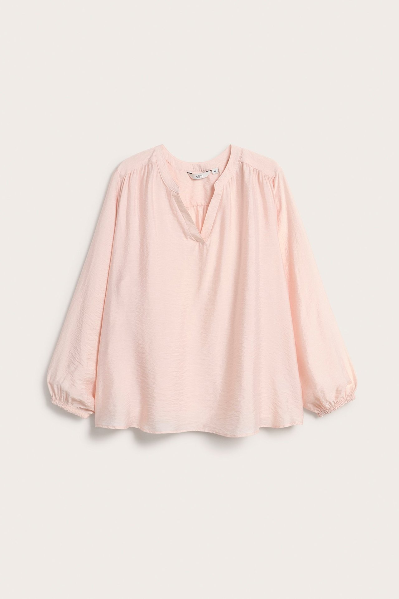 Widok z przodu jasnobeżowej bluzki z mieszanki wiskozy z dekoltem w serek i elastycznymi mankietami.