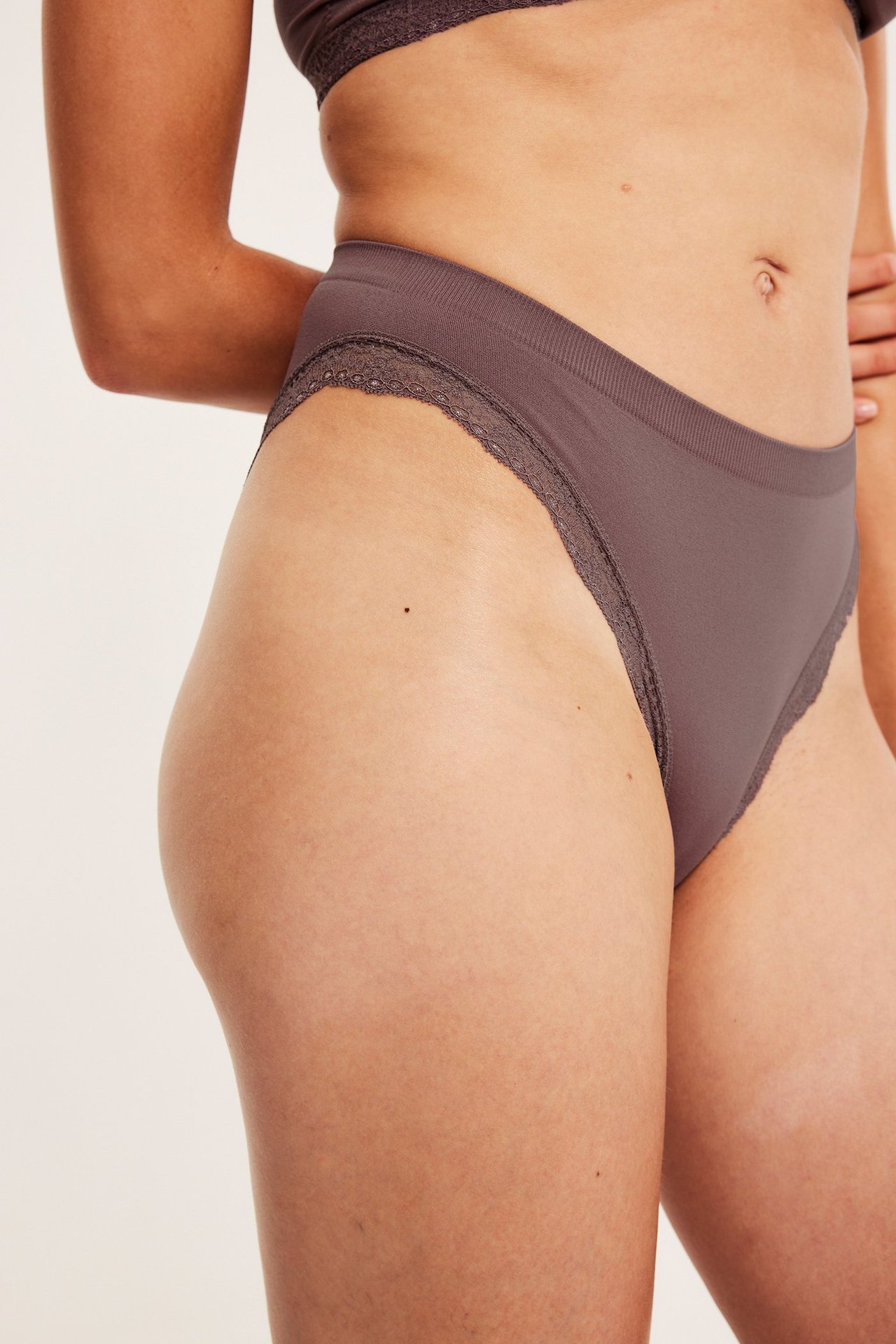 Naisen sivukuva yllään tummanroosat saumattomat pikkuhousut pitsireunalla ja yhteensopivat rintaliivit.