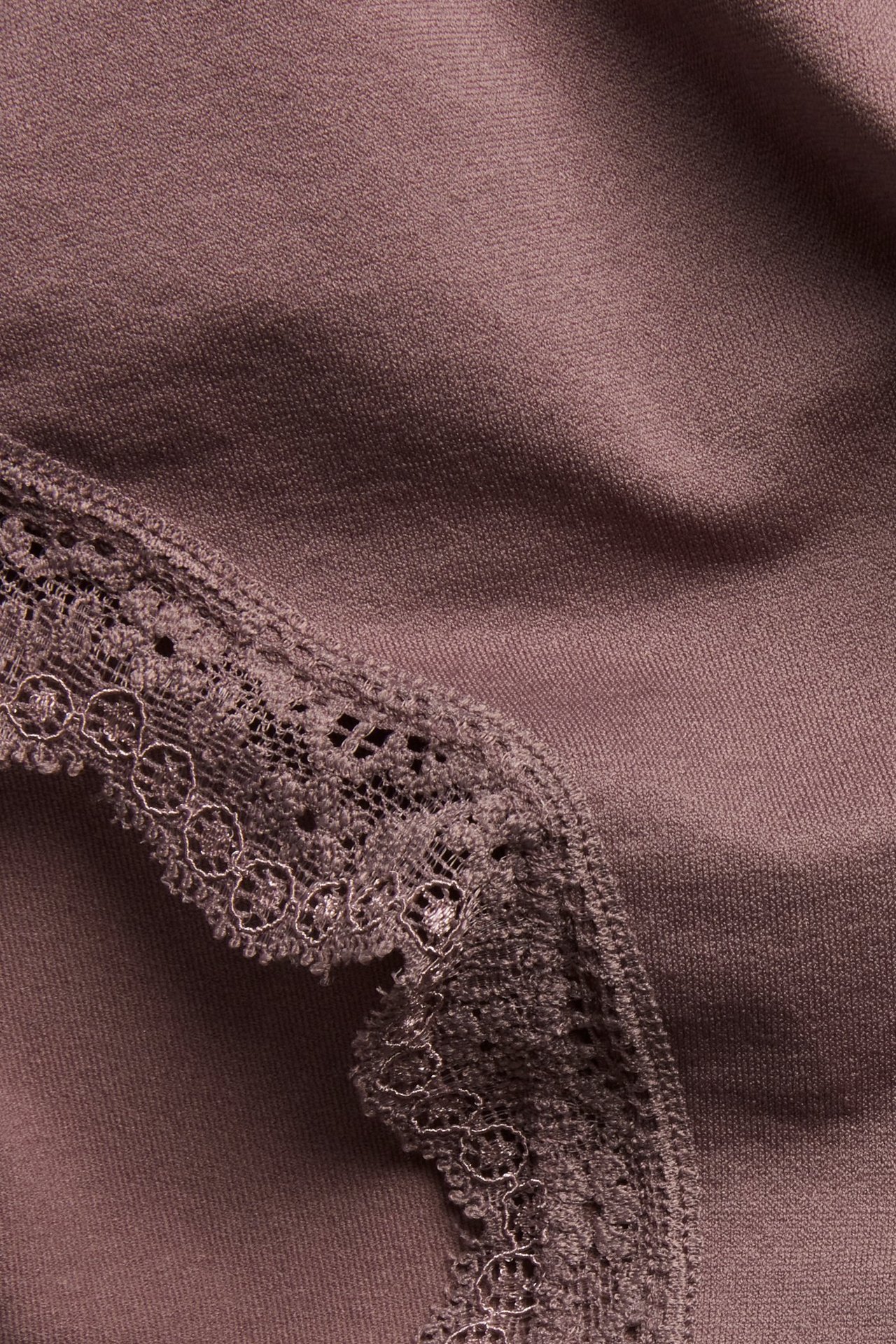 Zbliżenie na ciemnoróżowe bezszwowe figi z delikatną koronkową krawędzią.