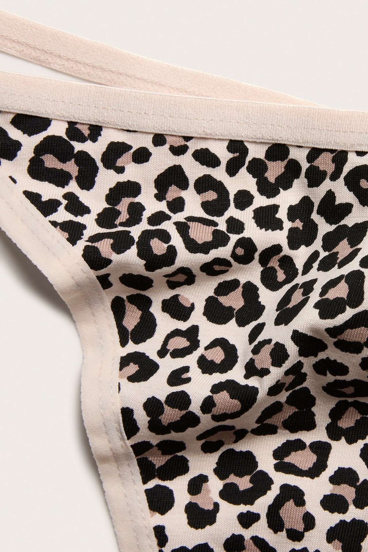 Lähikuva naisten beigestä leopardikuvioisesta string-alushoususta kapealla kuminauhalla.