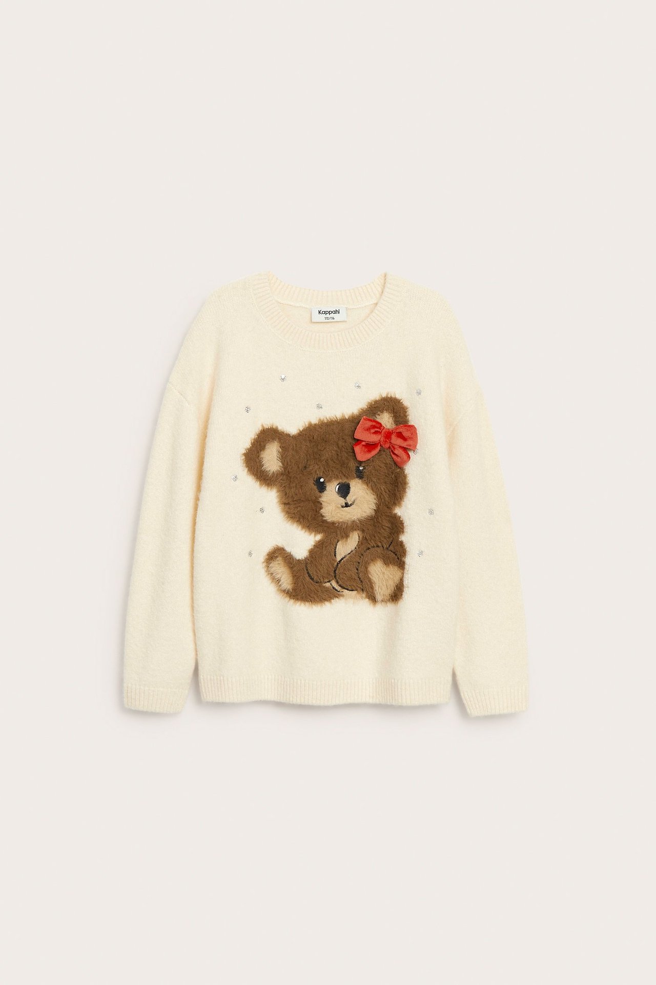 Edestäpäin: Lasten luonnonvalkoinen neulepusero, jossa ruskea nallekarhusovellus ja punainen rusetti.