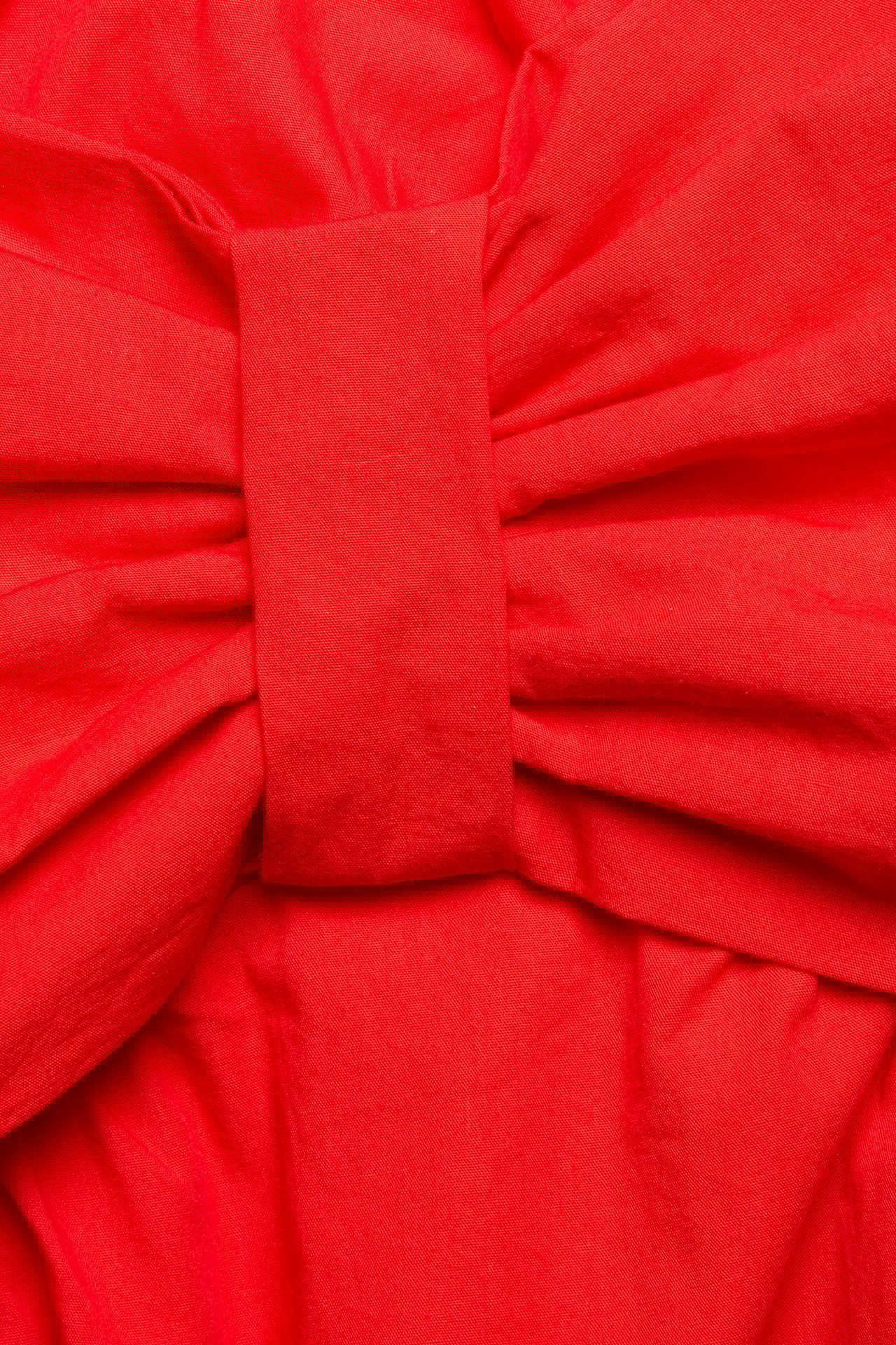 Zbliżenie wyraźnego detalu kokardy czerwonego bawełnianego topu.